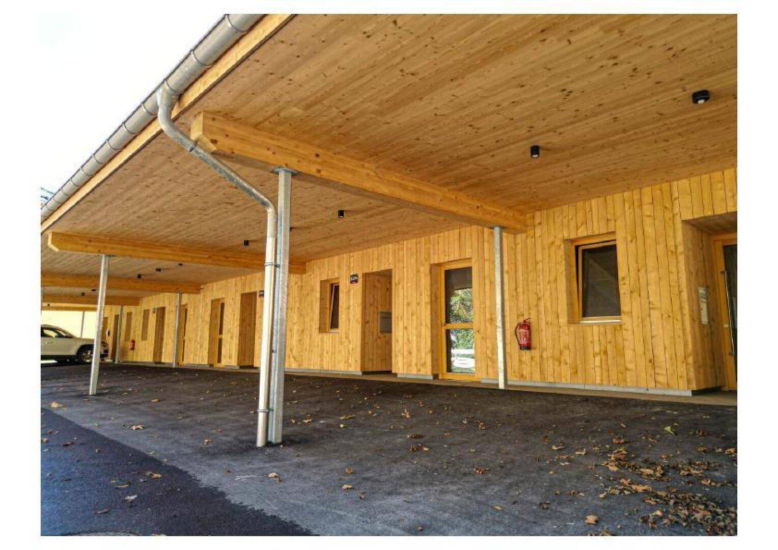 Überdachter Carport-Bereich mit Holzdecke und Zugang zu den Eingängen der Wohneinheiten.