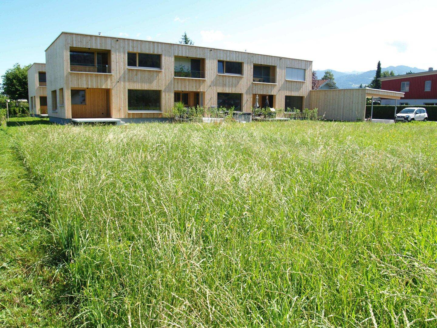 Modernes Holzgebäude in ländlicher Umgebung mit weitem Blick über grüne Wiesen.