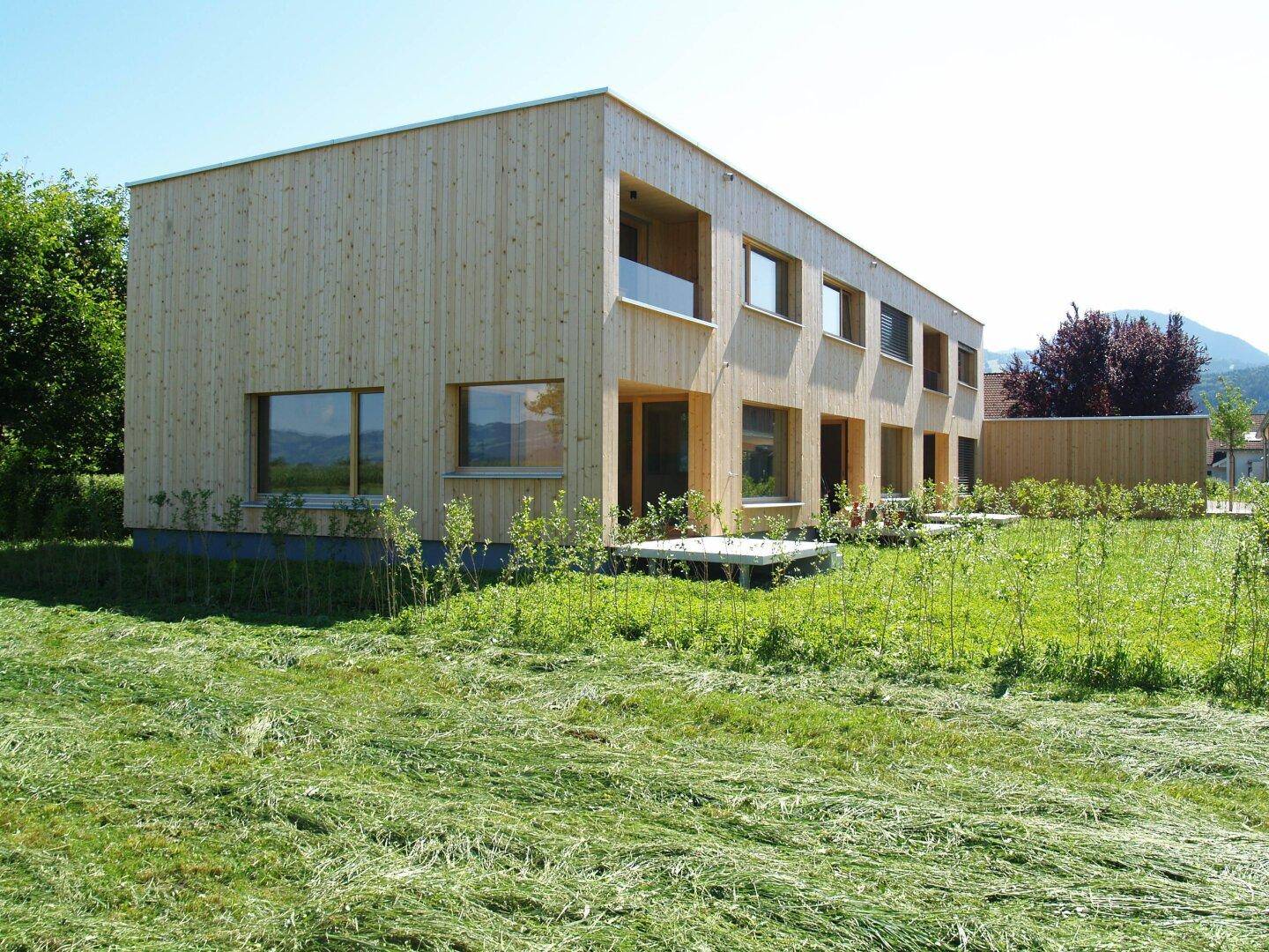 Einzelnes modernes Holzhaus mit klarer Architektur und einer kleinen Terrasse im Vordergrund.