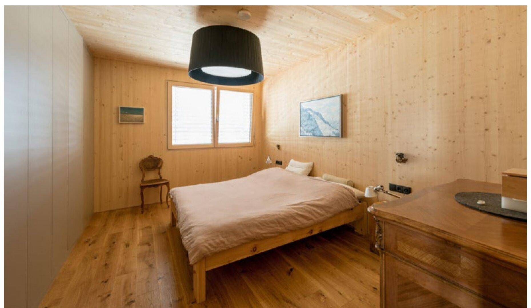 Gemütliches Schlafzimmer mit Holzwänden, Holzdecke und Holzboden, ausgestattet mit einem bequemen Bett.