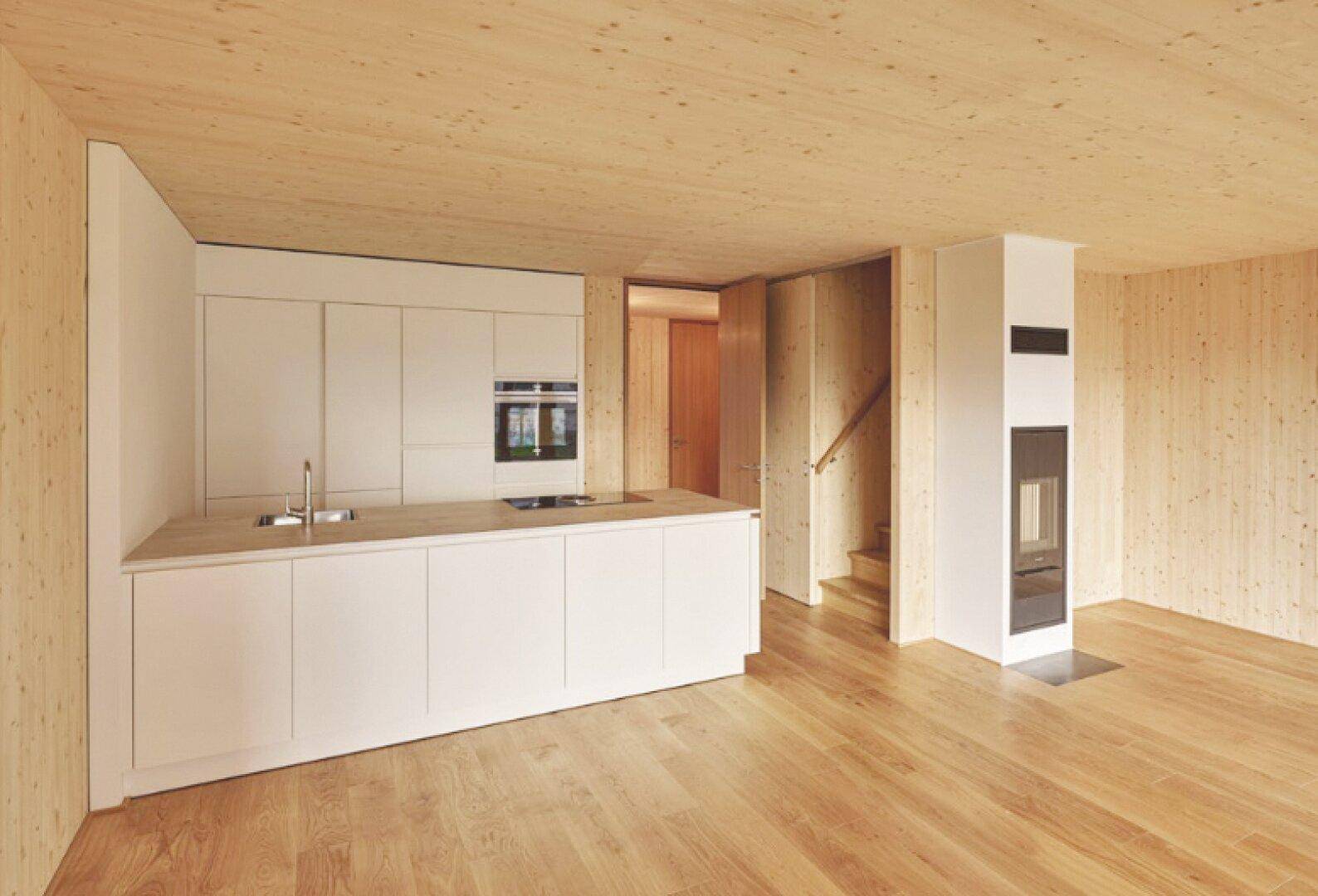 Moderne offene Küche mit weißer Insel, heller Holzverkleidung und integriertem Kamin.