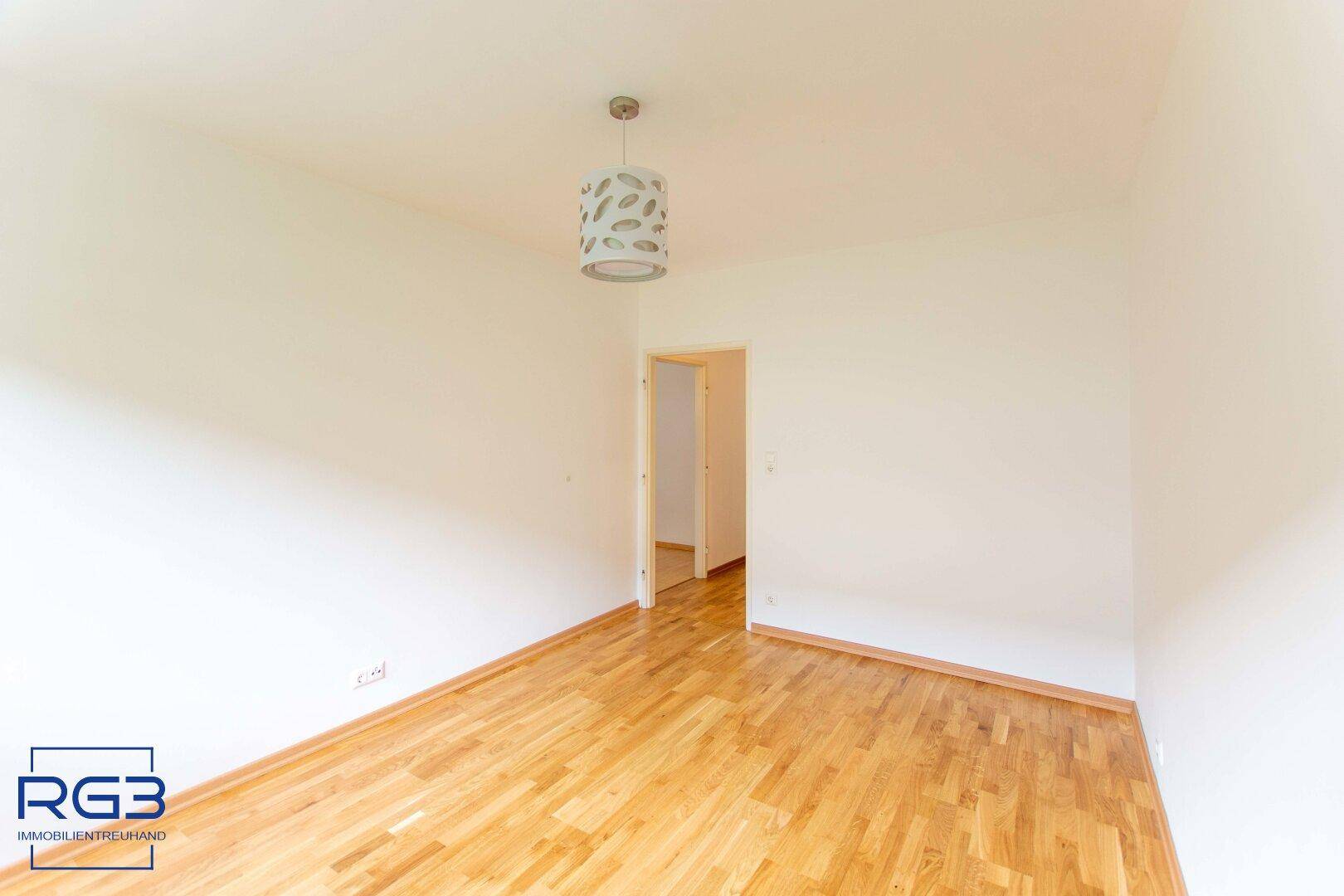 Helles Zimmer mit Parkettboden und schlichter Deckenleuchte, vielseitig nutzbar.