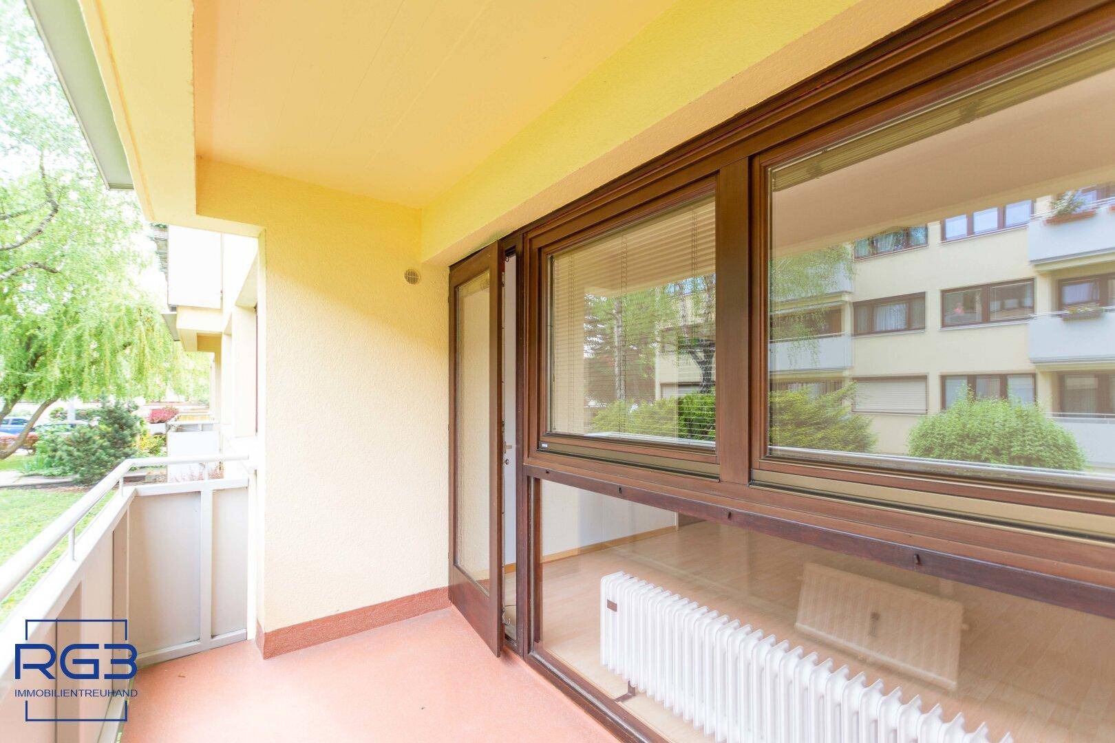Geräumiger Balkon mit gelber Fassade und Ausblick ins Grüne, ideal zum Entspannen.