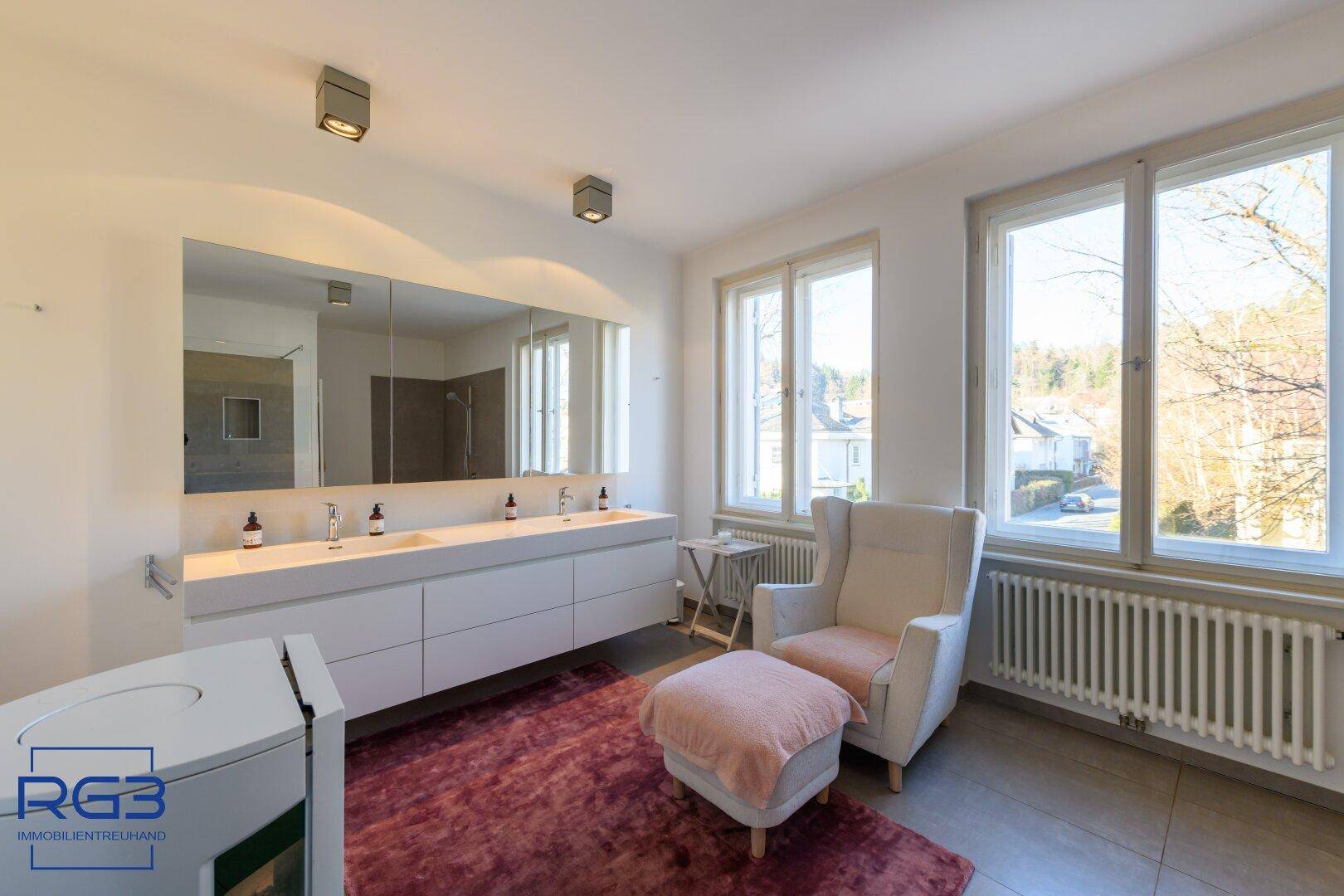 Geräumiges Badezimmer mit Doppelwaschbecken, großem Spiegel und Fenster mit Ausblick.