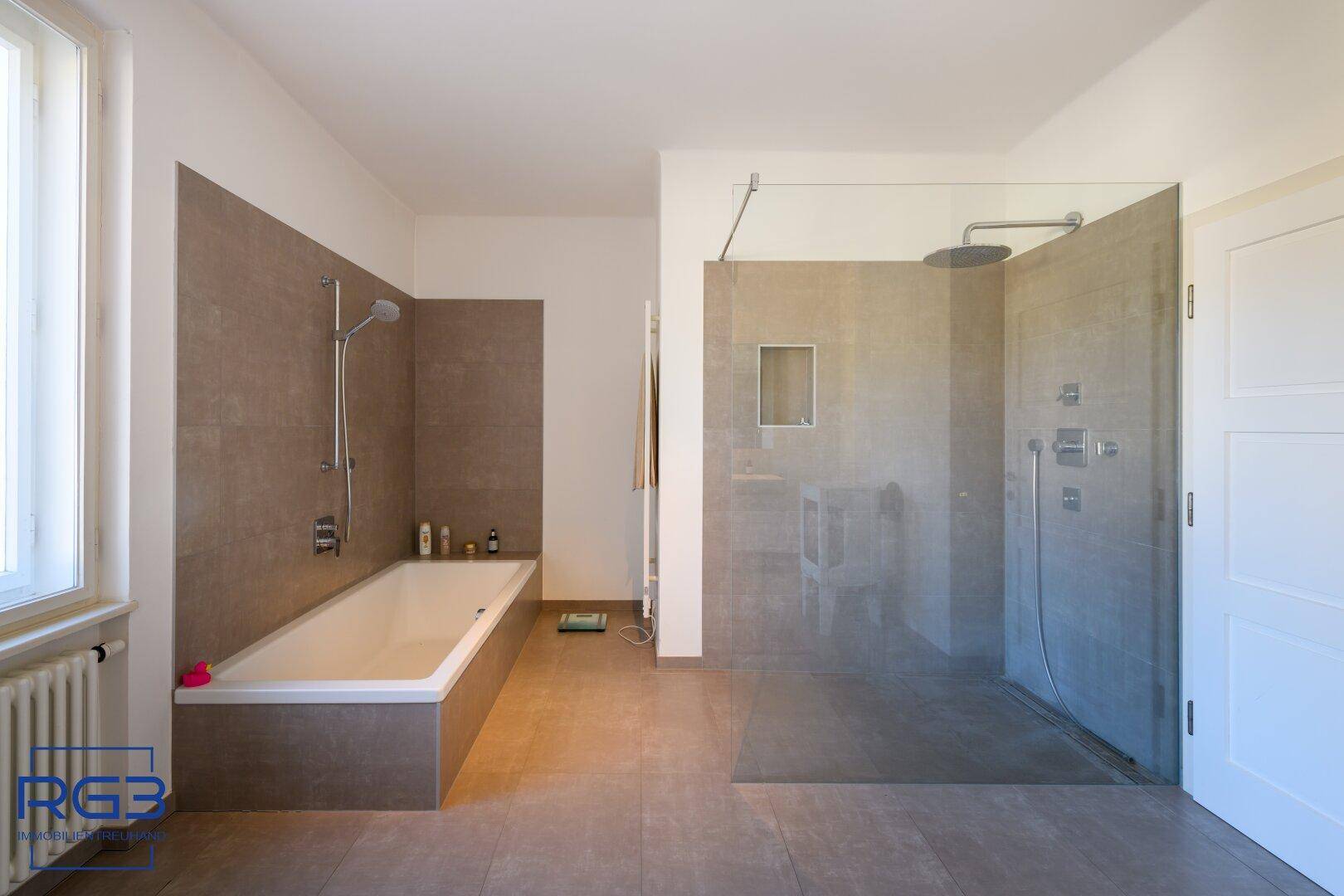 Modernes Badezimmer mit Badewanne, großer begehbarer Dusche und Fliesenboden.