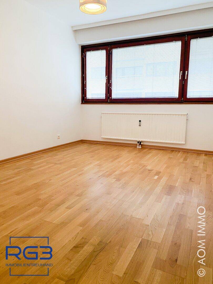 Freundliches Zimmer mit hellem Parkettboden und Fenster mit Jalousien, ideal als Schlaf- oder Arbeitszimmer.