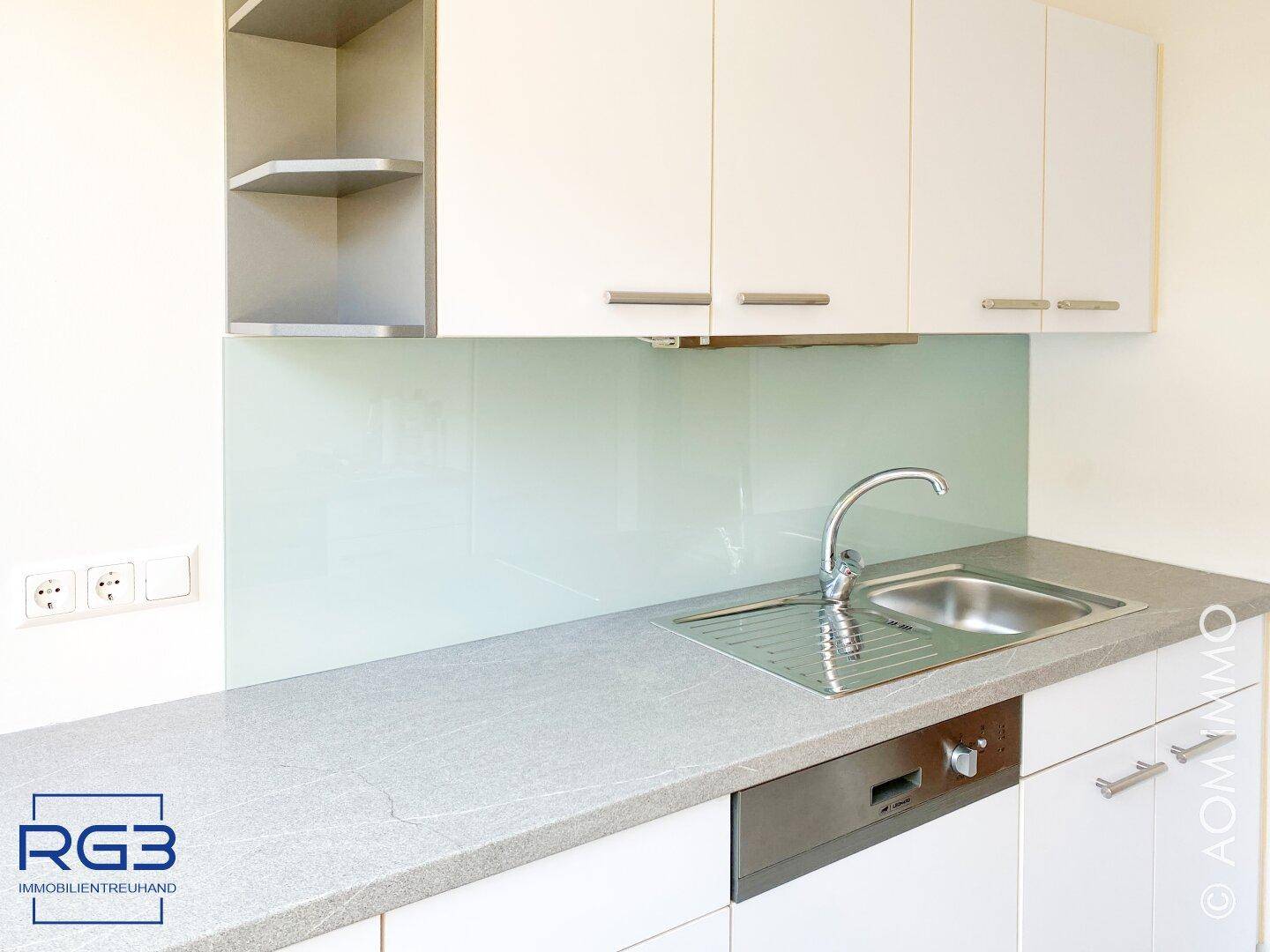 Detailansicht der Küche mit Spülbecken, modernen Armaturen und weißer Schrankfront.