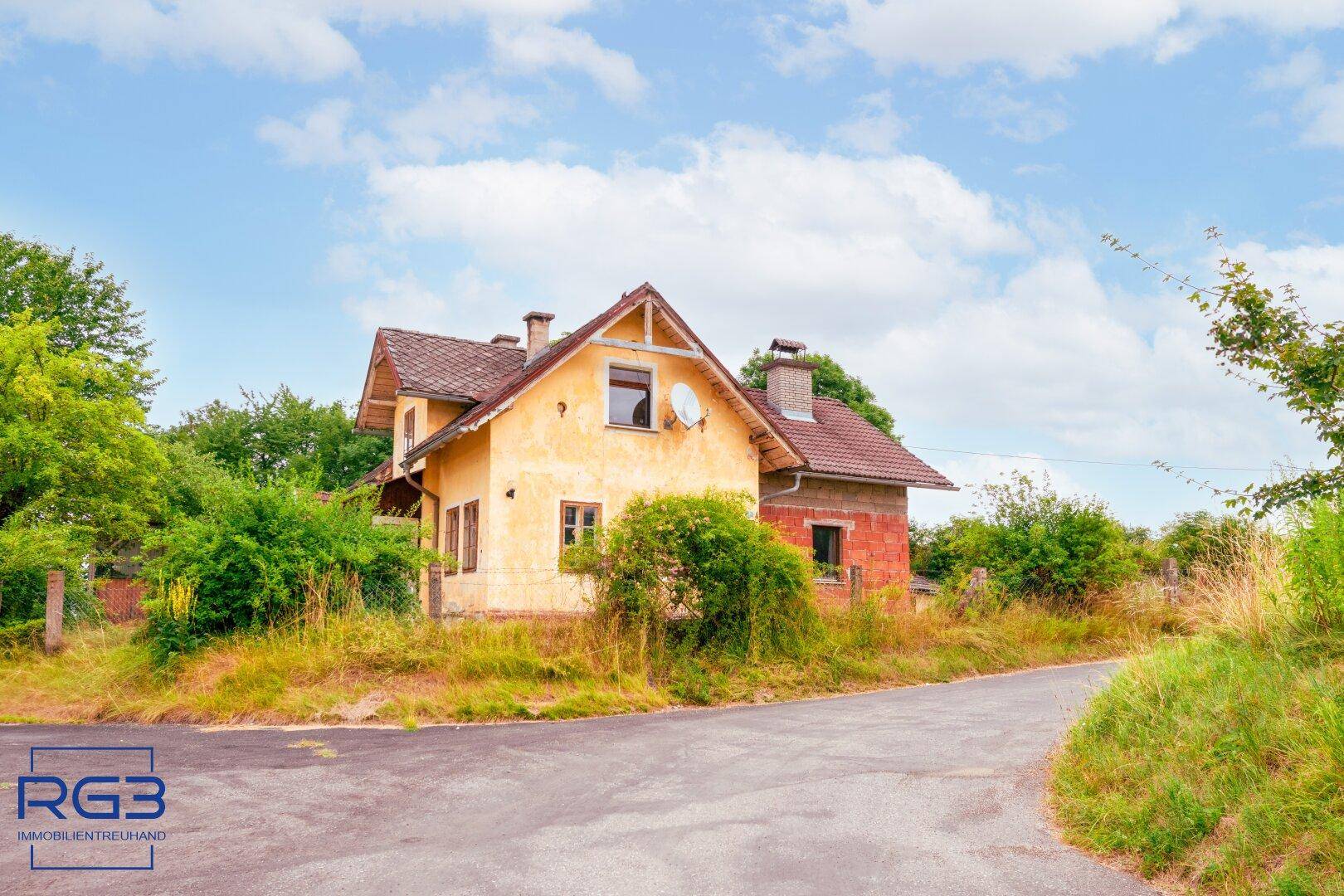 Älteres Wohnhaus mit Satteldach und renovierungsbedürftiger Fassade in ländlicher Umgebung.