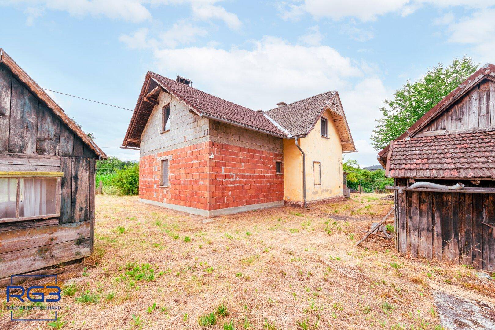Ländliches Wohnhaus mit Nebengebäuden, umgeben von viel Grün und Natur.