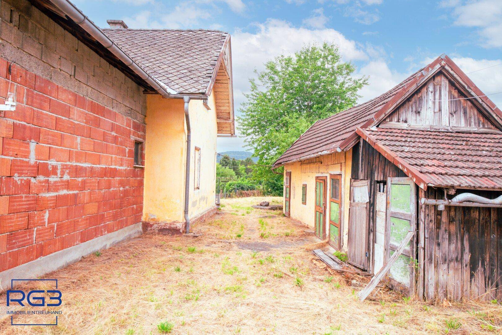 Zwischenraum zwischen zwei Nebengebäuden mit Blick auf das Hauptgebäude und die Landschaft.