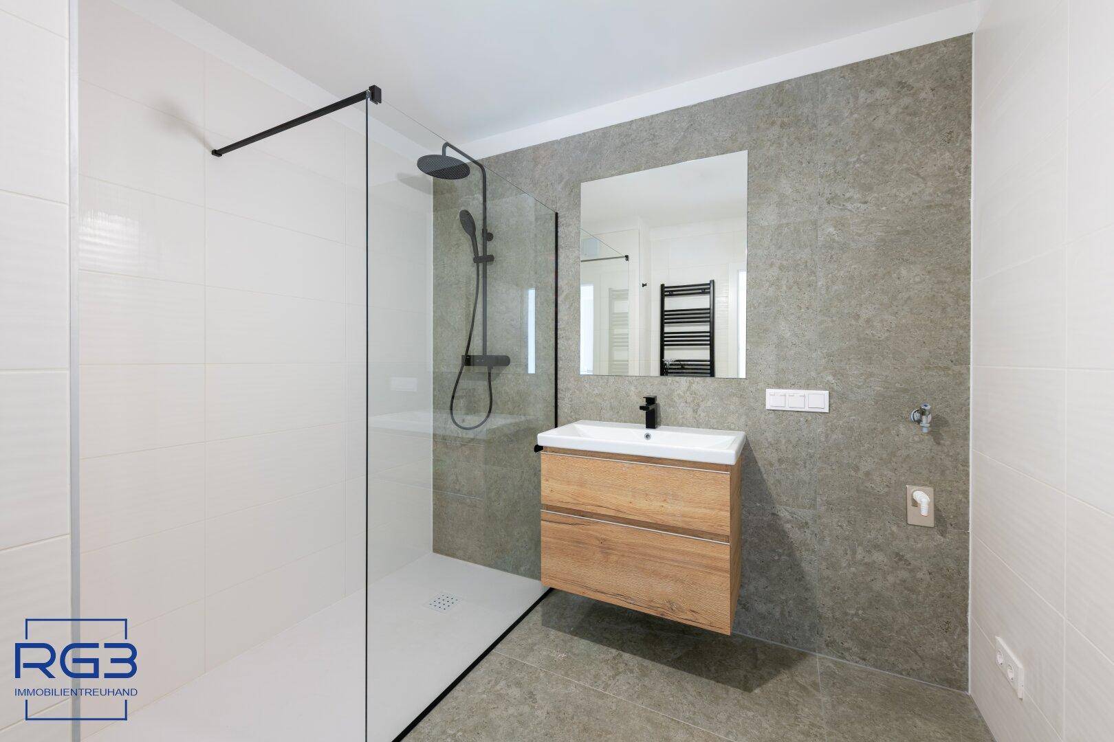 Modernes Badezimmer mit begehbarer Dusche, Holzwaschtisch und grauen Fliesen.