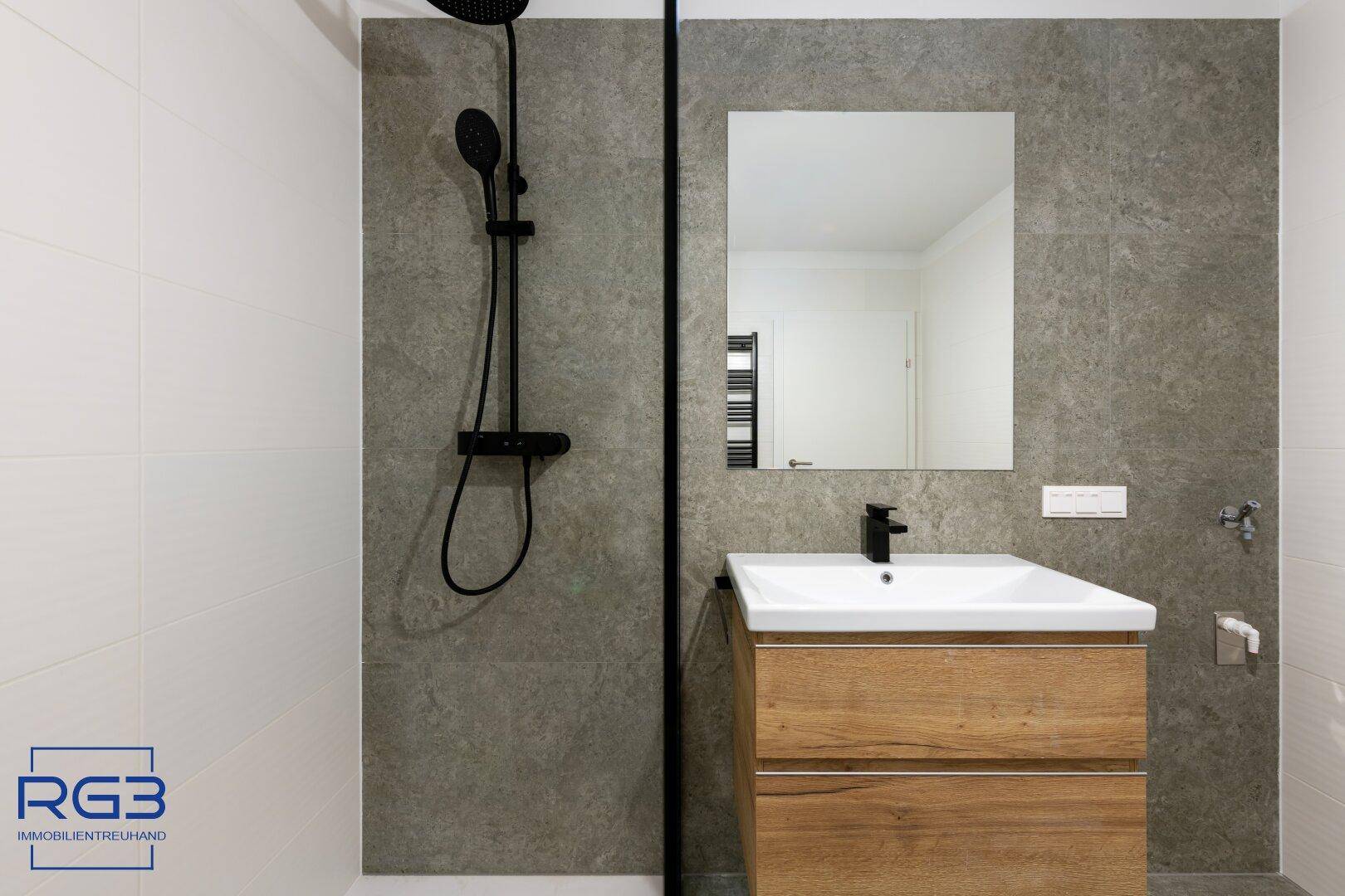 Detailansicht des modernen Badezimmers mit begehbarer Dusche und stilvollem Waschtisch.