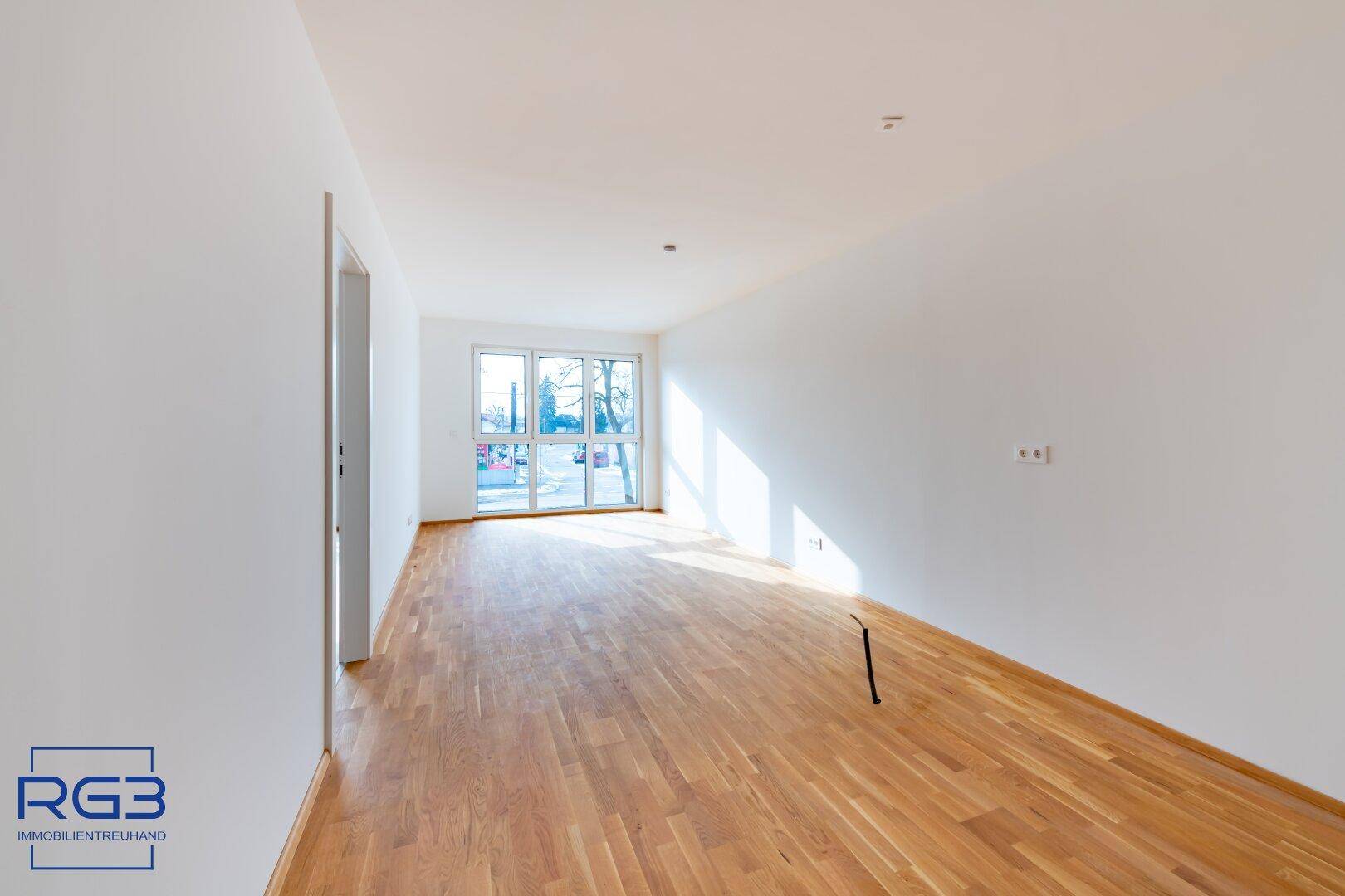 Geräumiges, helles Zimmer mit Parkettboden und großen Fenstern, ideal für Wohnzwecke.