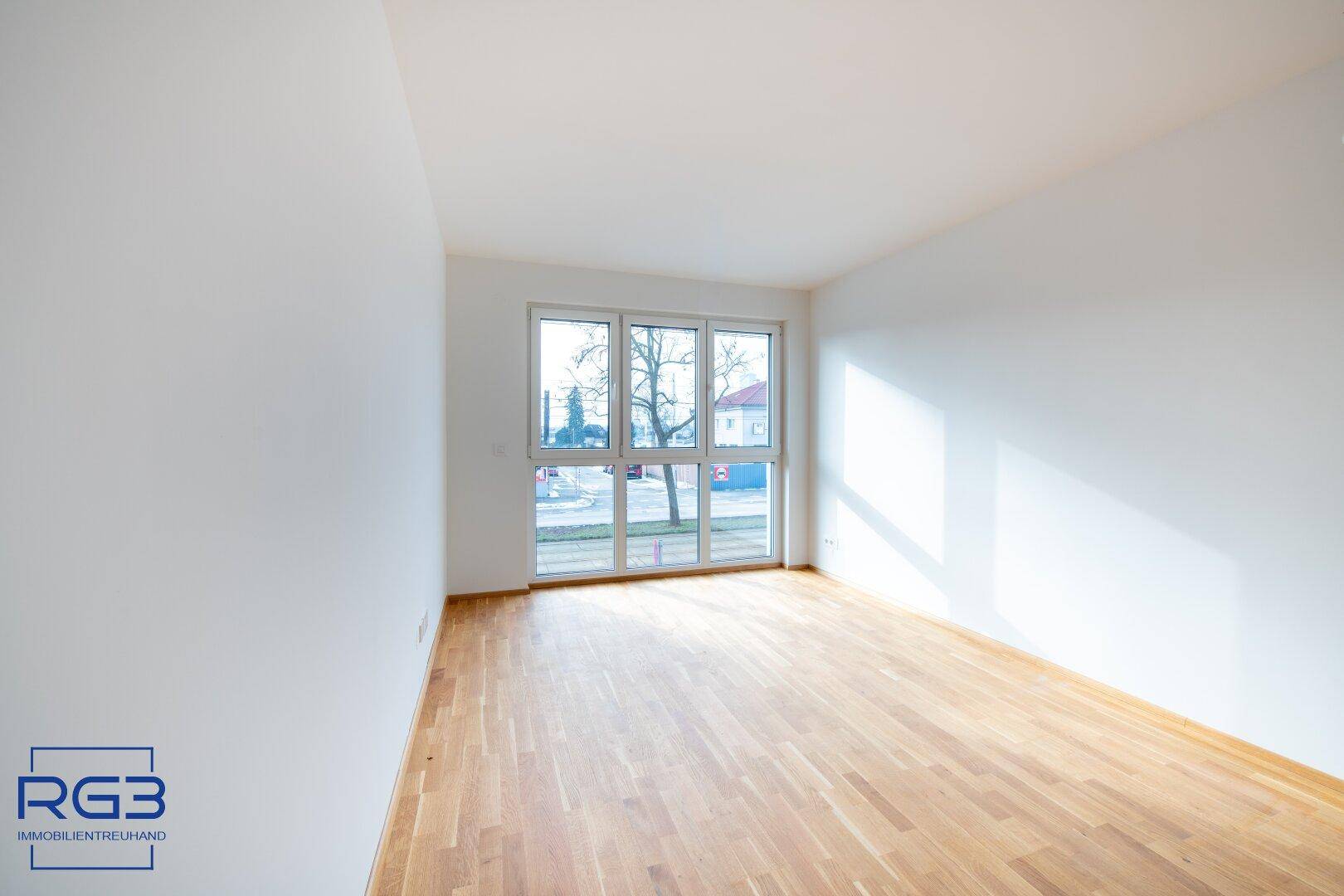 Geräumiges, helles Zimmer mit Parkettboden und großen Fenstern, ideal für vielfältige Nutzung.