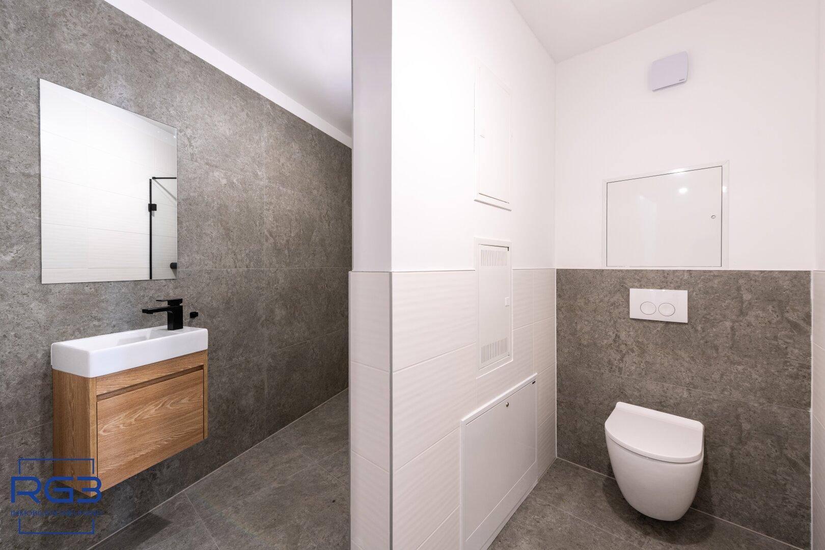 Modernes Gäste-WC mit Wand-WC, kleinem Waschbecken und stilvollen grauen Fliesen.