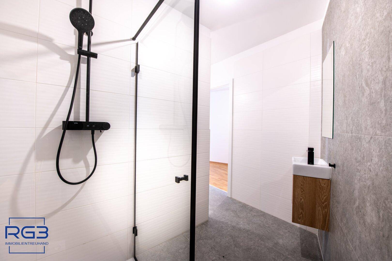 Geräumige begehbare Dusche mit modernen schwarzen Armaturen und weißen Wandfliesen.