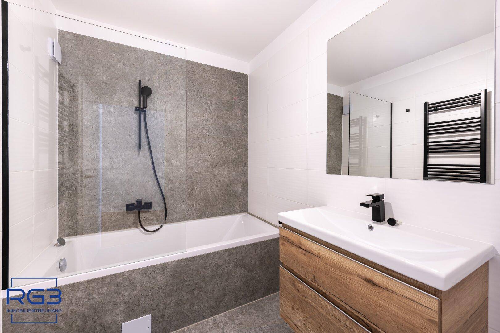 Elegantes Badezimmer mit Badewanne, Holzwaschtisch und beheiztem Handtuchhalter in Schwarz.