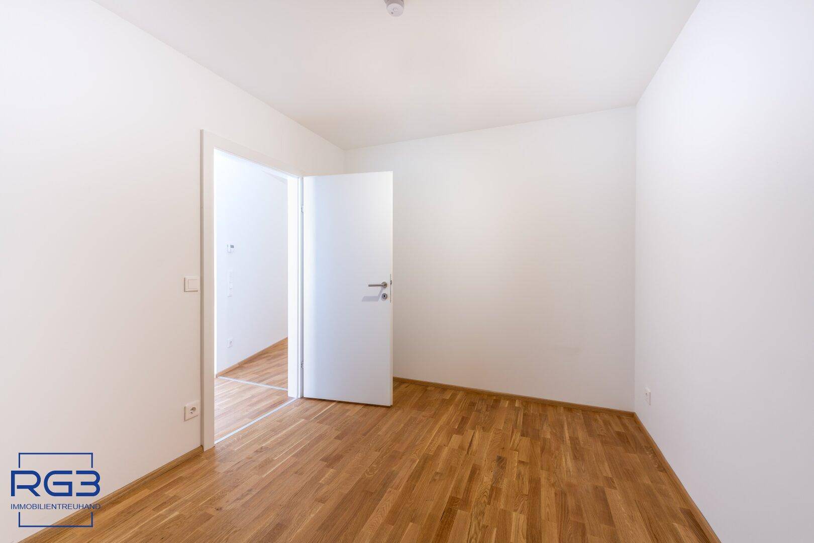 Helles Zimmer mit Parkettboden und weiß gestrichenen Wänden, bereit zur individuellen Gestaltung.