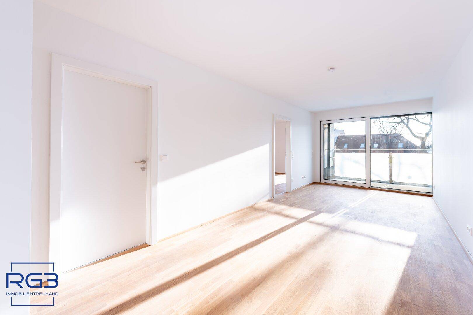 Lichtdurchfluteter Raum mit Holzboden und großem Fenster, das den Blick nach draußen freigibt.