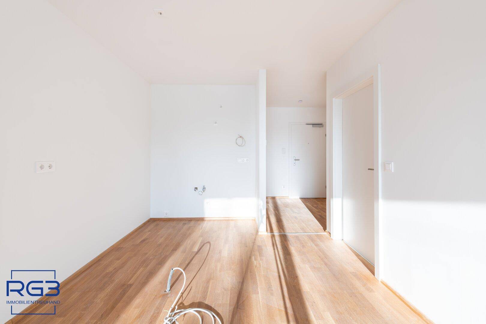 Leerer Raum mit Holzboden und Wandanschlüssen, bereit für individuelle Gestaltung und Nutzung.