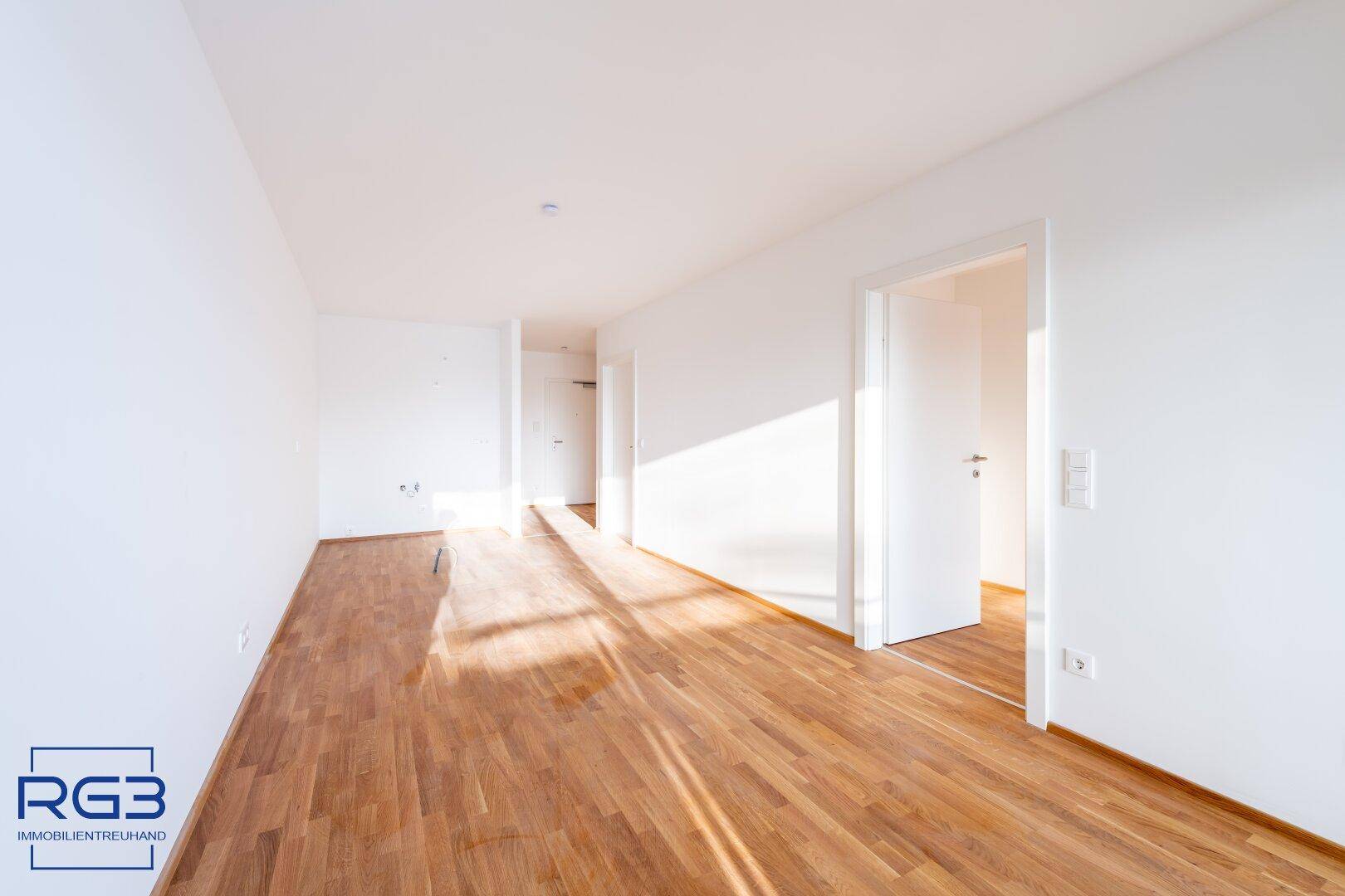 Geräumiger, heller Raum mit Holzboden und mehreren Türen, der vielseitig nutzbar ist.