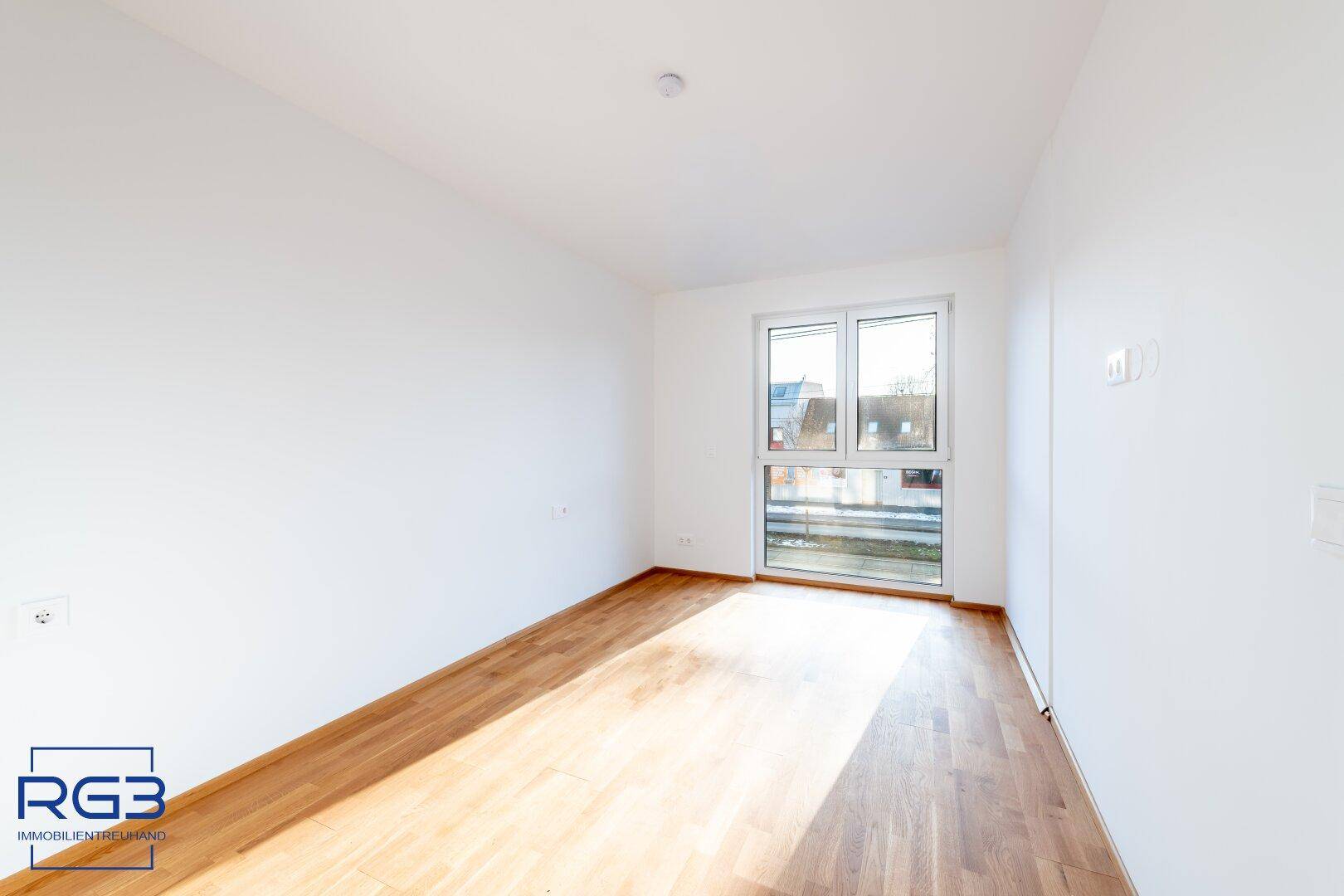 Helles Zimmer mit Holzboden und Fenster, das sich gut als Schlaf- oder Arbeitszimmer eignet.