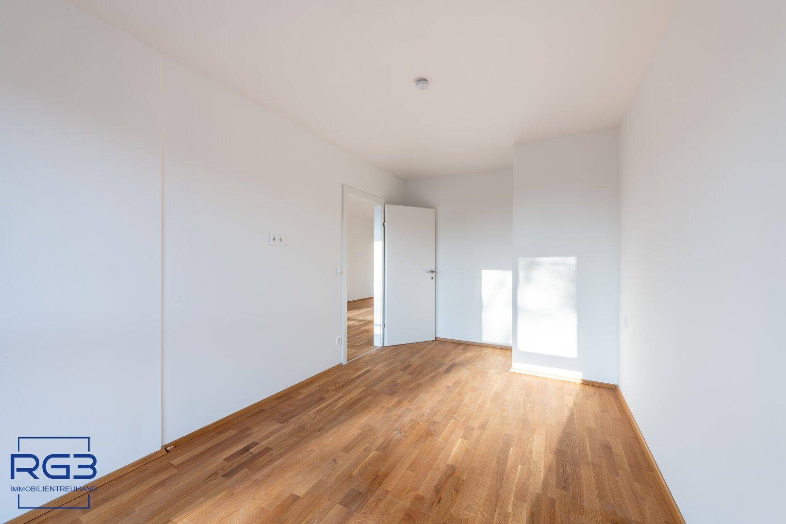 Geräumiger, heller Raum mit Holzboden und offener Tür, der vielseitige Nutzungsmöglichkeiten bietet.