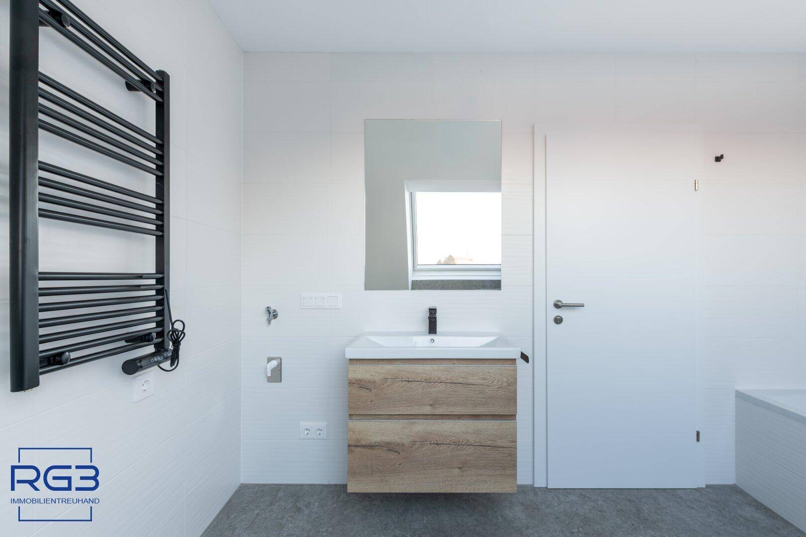 Modernes Badezimmer mit Holzelementen, Einzelwaschbecken und beheiztem Handtuchhalter.