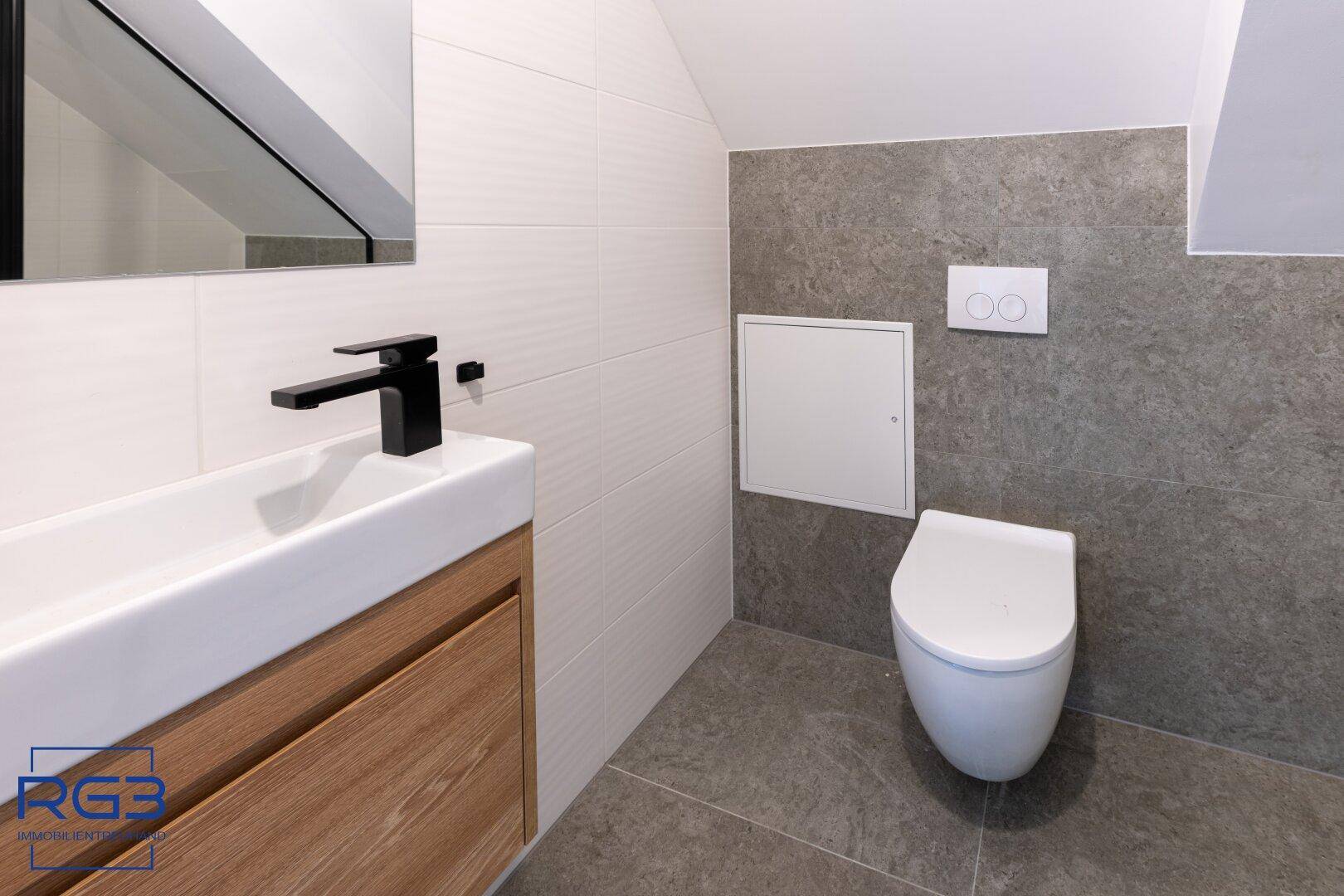 Modernes WC mit wandhängender Toilette und stilvollem Einzelwaschbecken.