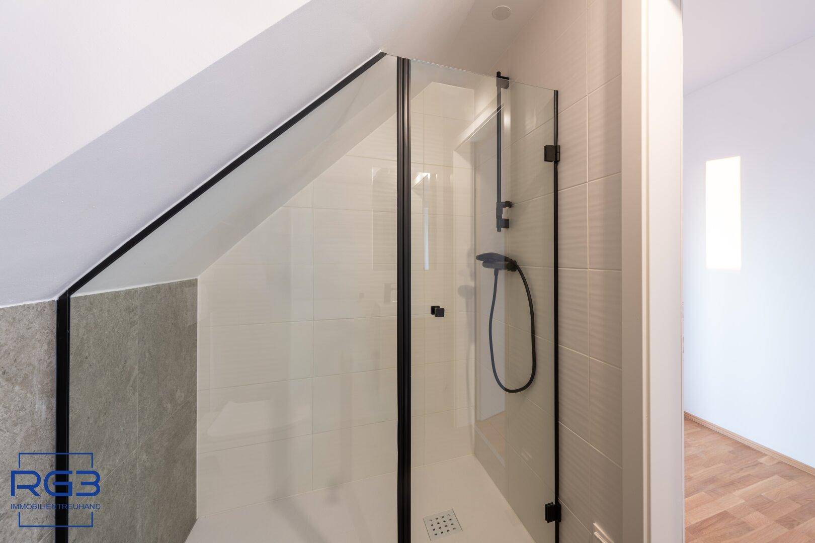 Moderne Duschkabine mit schwarzem Rahmen und schrägen Wänden im Badezimmer.