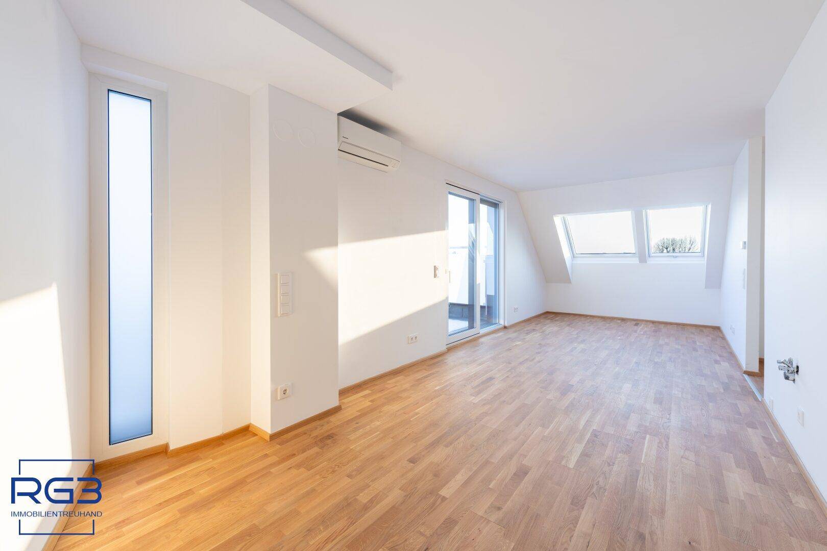 Lichtdurchfluteter Raum mit Parkettboden, Dachfenstern und Zugang zur Terrasse.