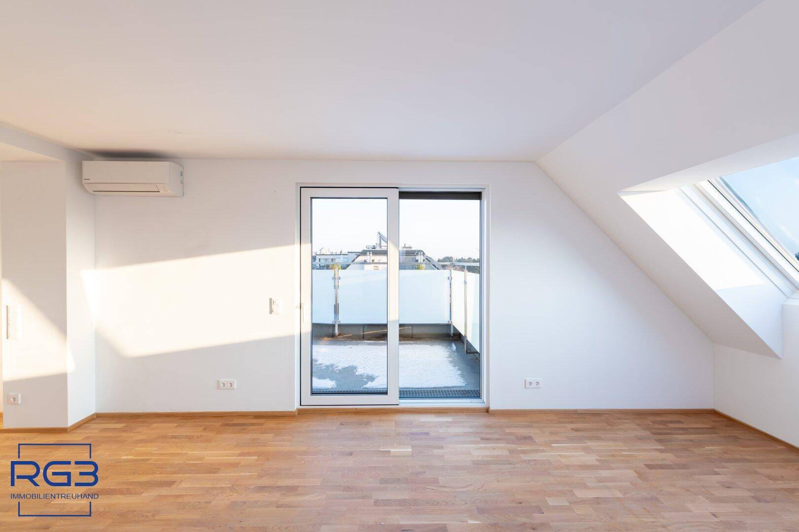 Heller Wohnraum mit Parkettboden, Dachfenster und direktem Zugang zur sonnigen Terrasse.