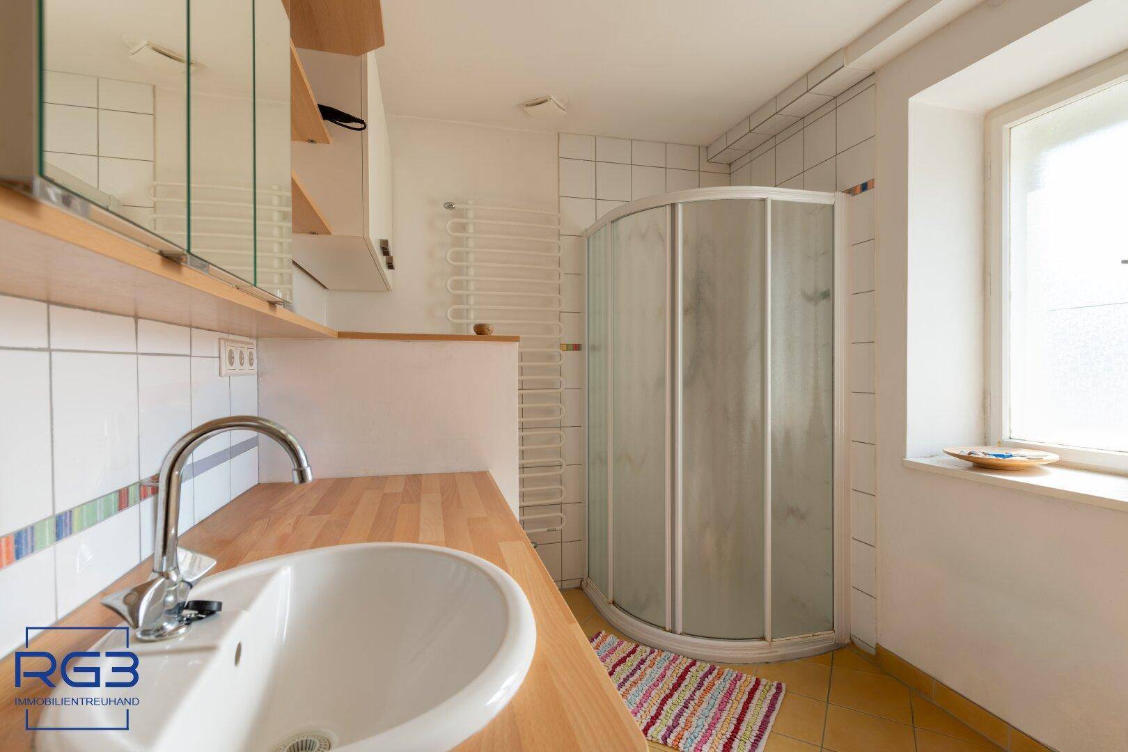 Modernes Badezimmer mit Duschkabine, Einzelwaschbecken und beheiztem Handtuchhalter.