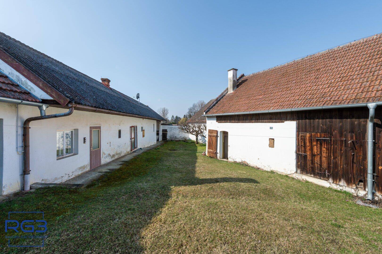 Weitläufiger Innenhof zwischen mehreren historischen Gebäuden mit grüner Rasenfläche.
