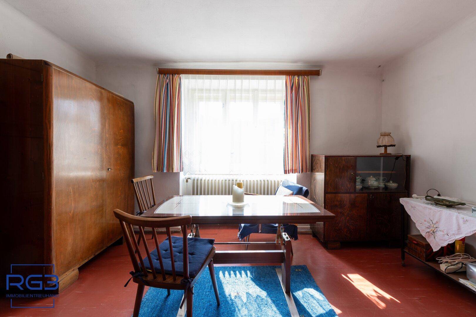 Heller Essbereich mit Holztisch, Stühlen und einem großen Fenster mit bunten Vorhängen.