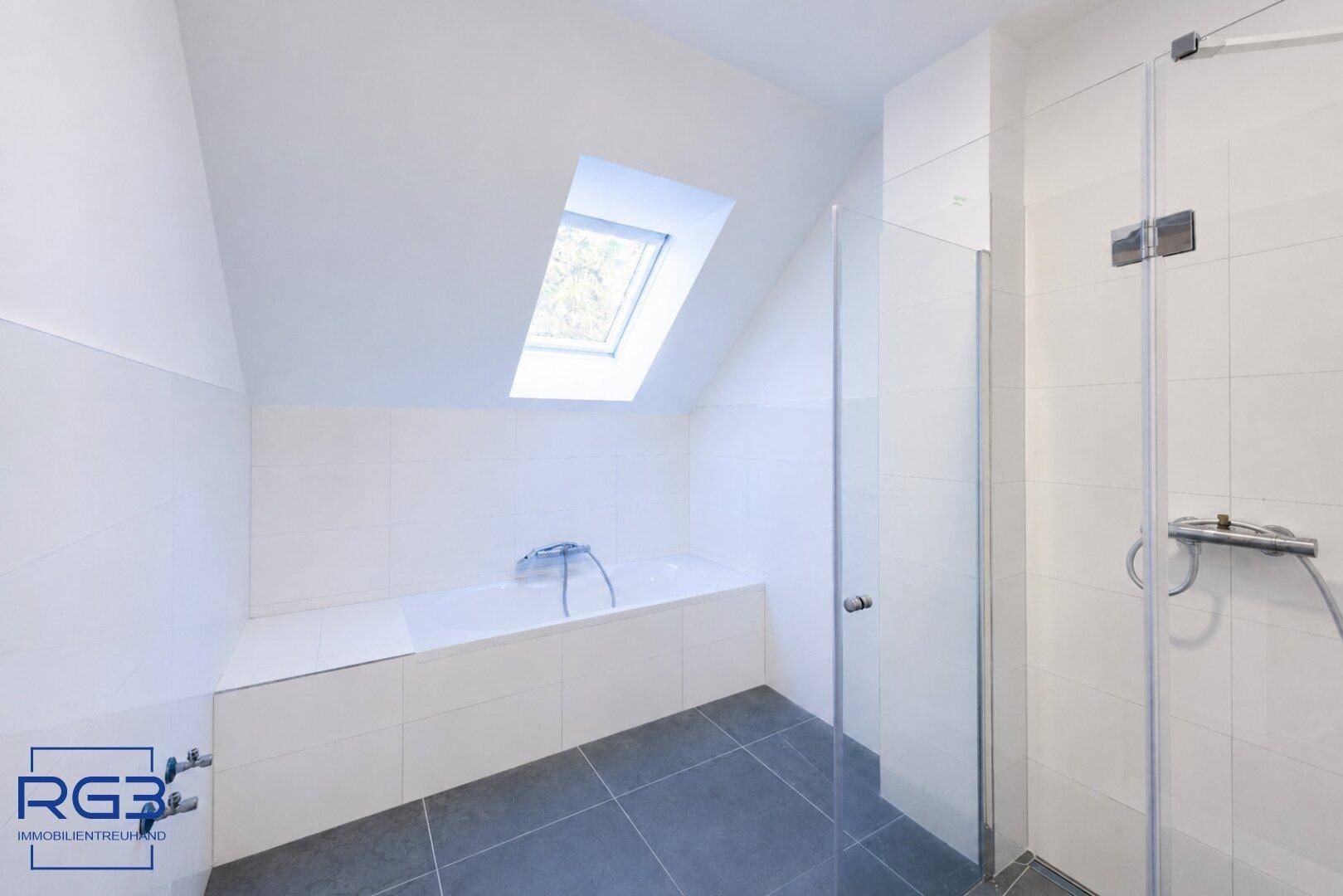 Modernes Badezimmer im Dachgeschoss mit Badewanne, Dusche, Fliesen und Dachfenster.