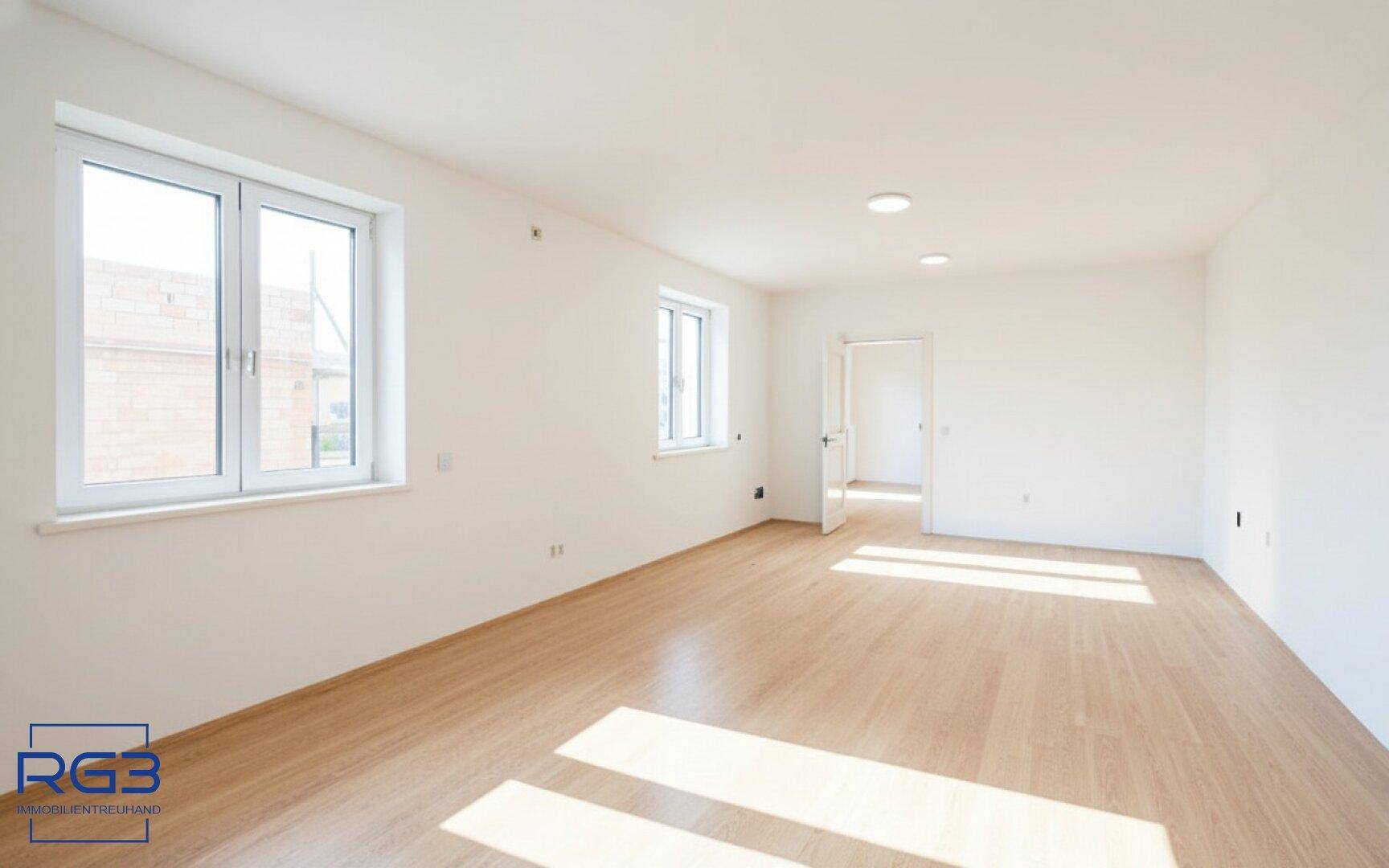 Helles Wohnzimmer mit großen Fenstern, Laminatboden und weiß gestrichenen Wänden.