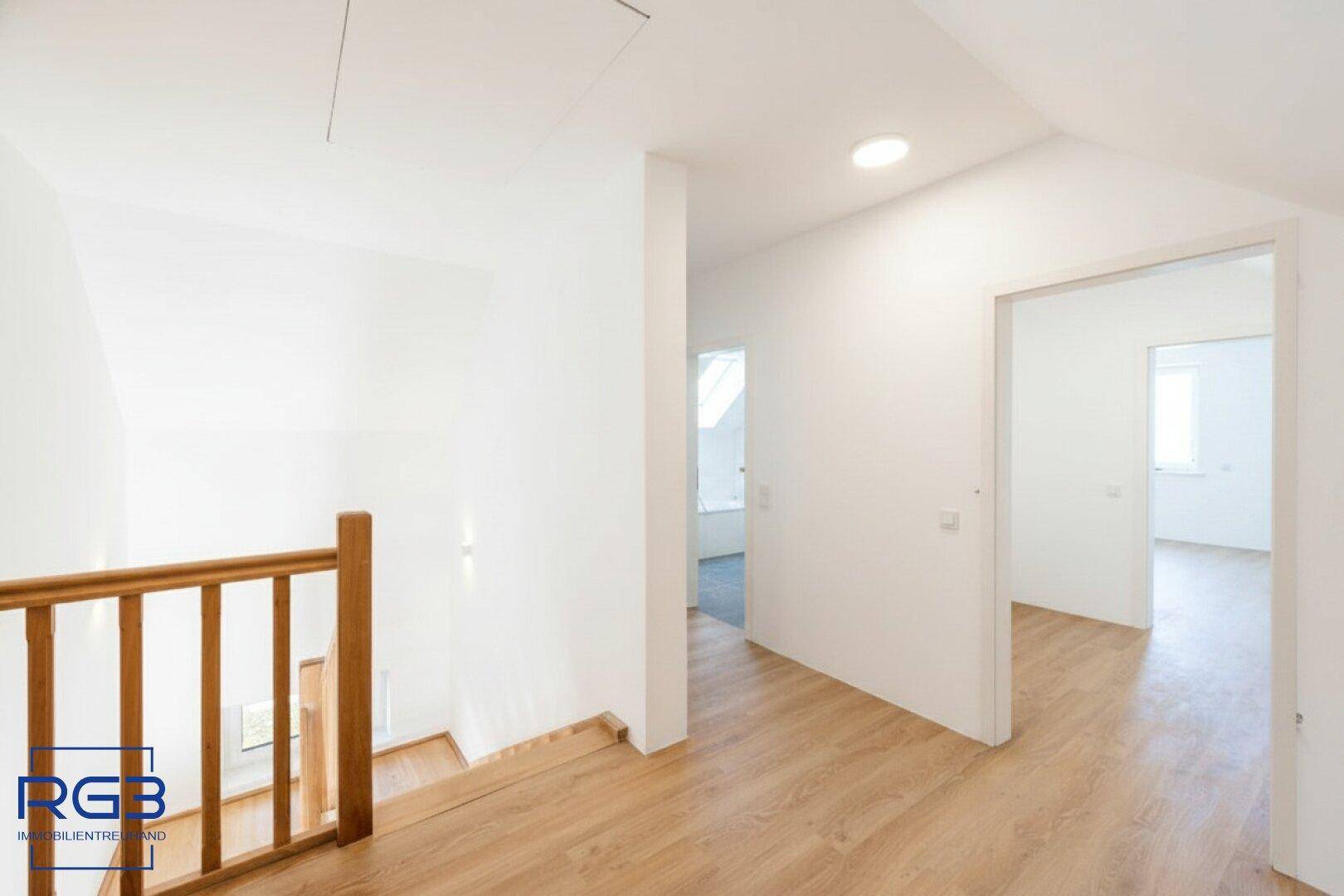 Heller Flur im Obergeschoss mit Laminatboden und Zugang zu weiteren Zimmern.