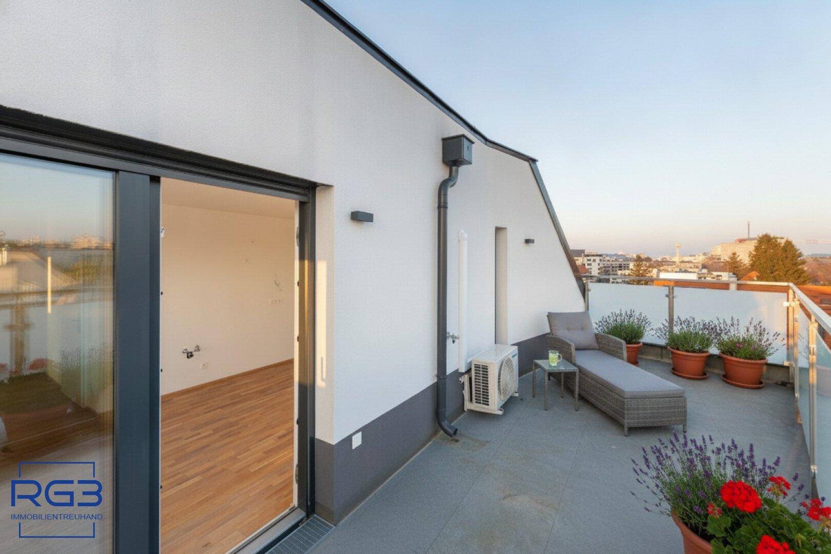 Sonnige Terrasse mit Outdoor-Möbeln, Topfpflanzen und Blick auf die Umgebung.