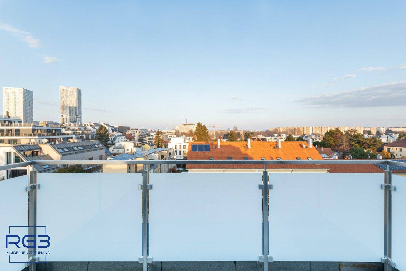 Terrasse mit Glasgeländer und weitem Blick auf die Stadt und moderne Hochhäuser.