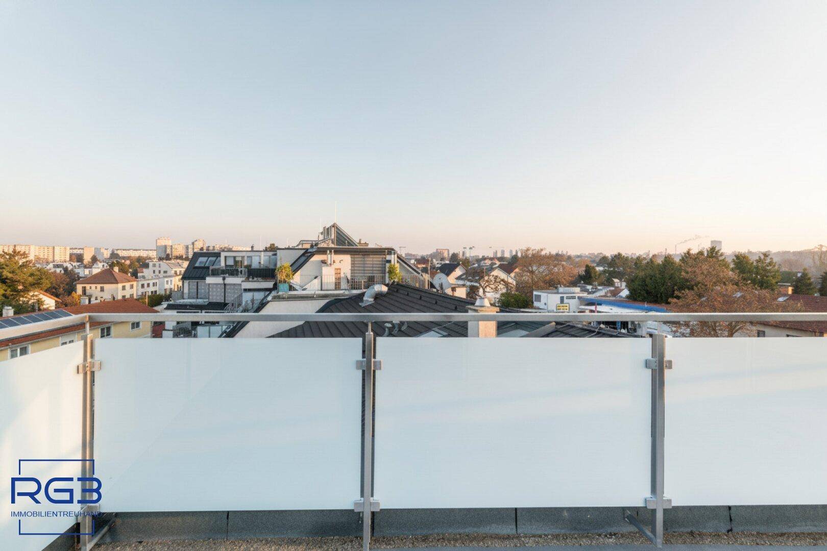 Weitläufige Terrasse mit Glasgeländer und Panoramablick über die Dächer der Stadt.