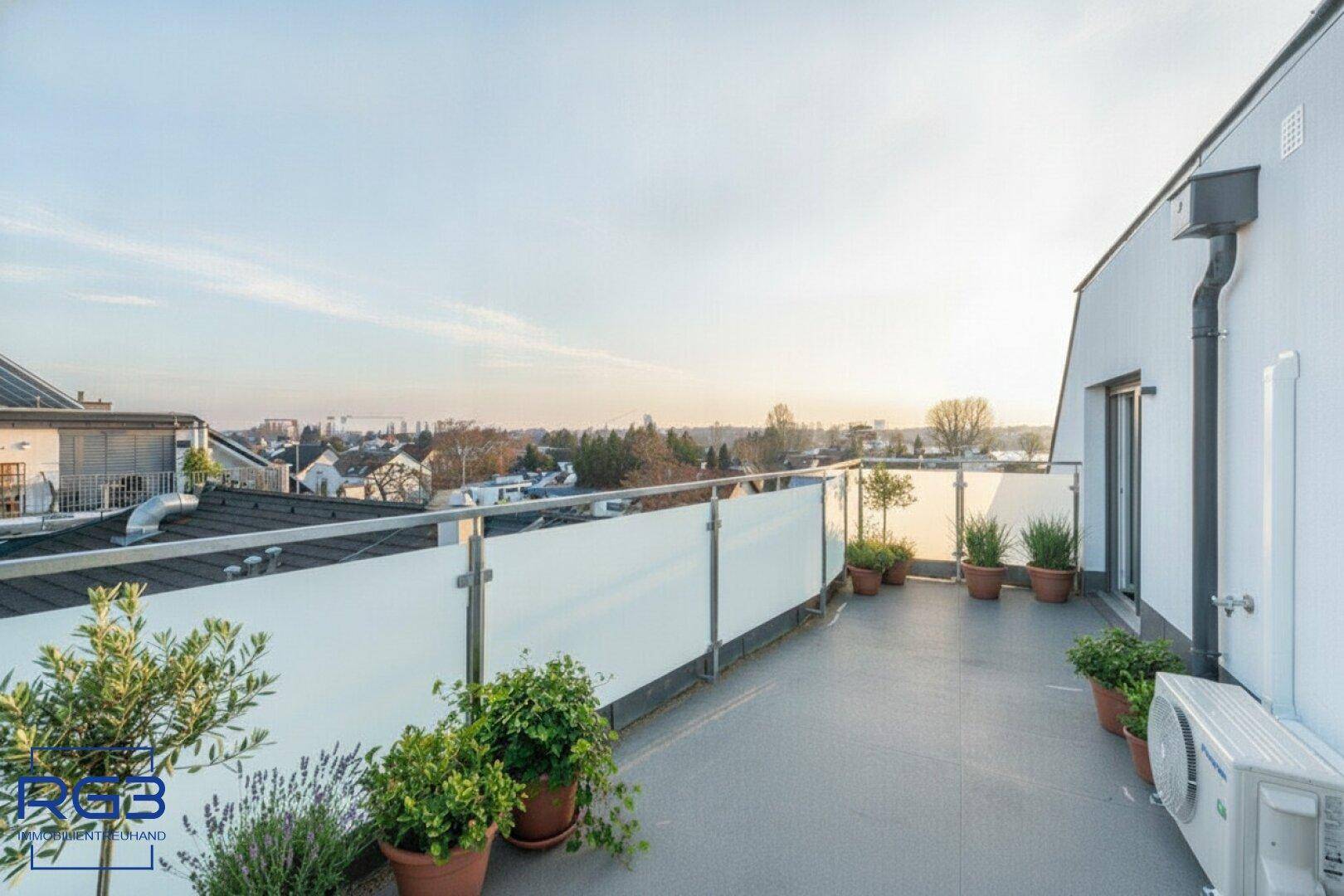 Geräumige Terrasse mit Topfpflanzen, Klimaanlage und Panoramablick über die Umgebung.