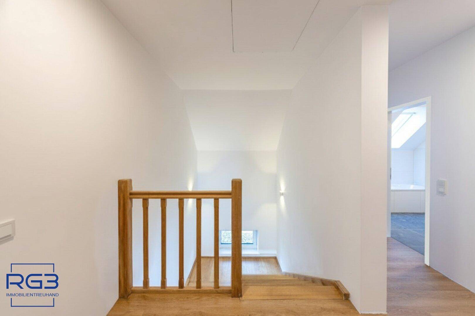 Heller Flur mit Holzgeländer und Zugang zu weiteren Räumen im Obergeschoss.