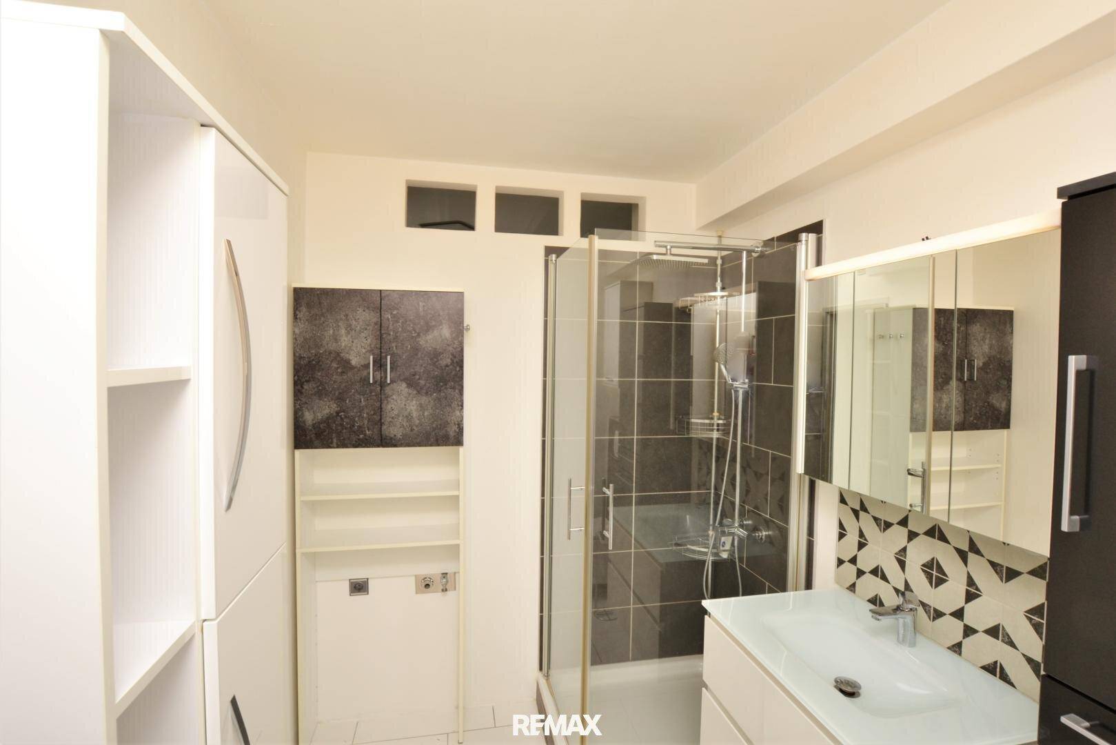 Modernes Badezimmer mit Duschkabine, Waschbecken und praktischen Ablagemöglichkeiten.