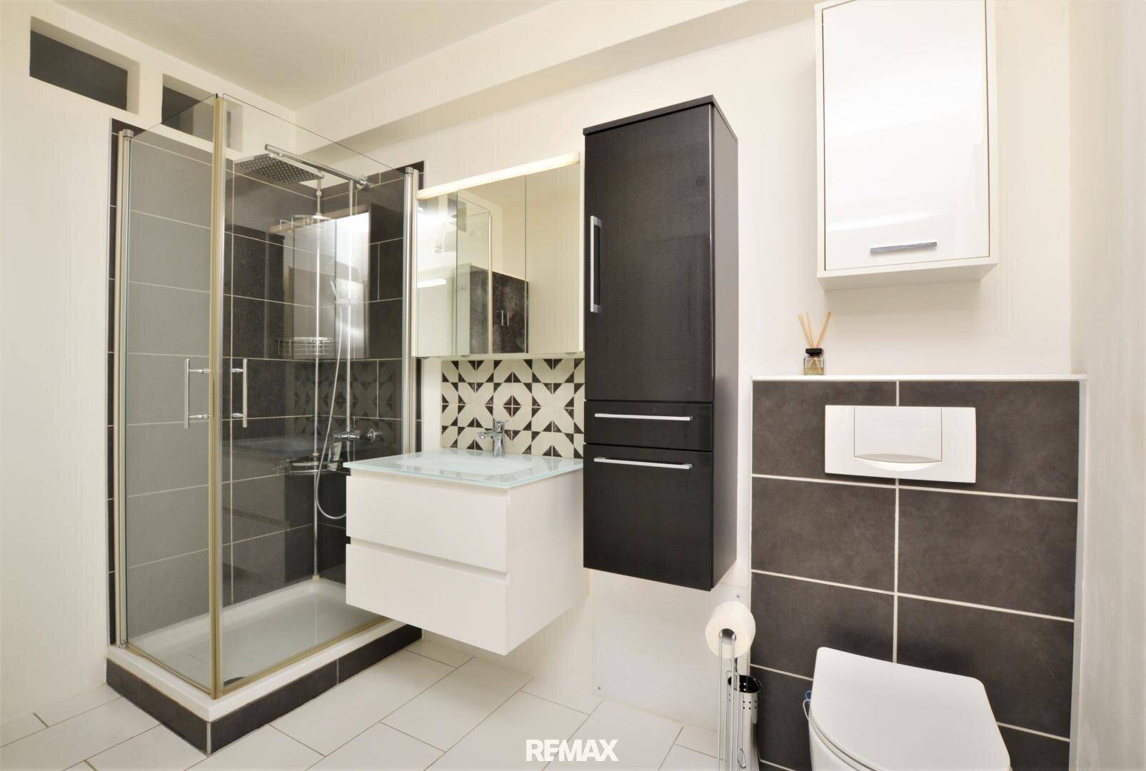Helles Badezimmer mit Duschkabine, wandhängendem WC und modernem Waschbecken.