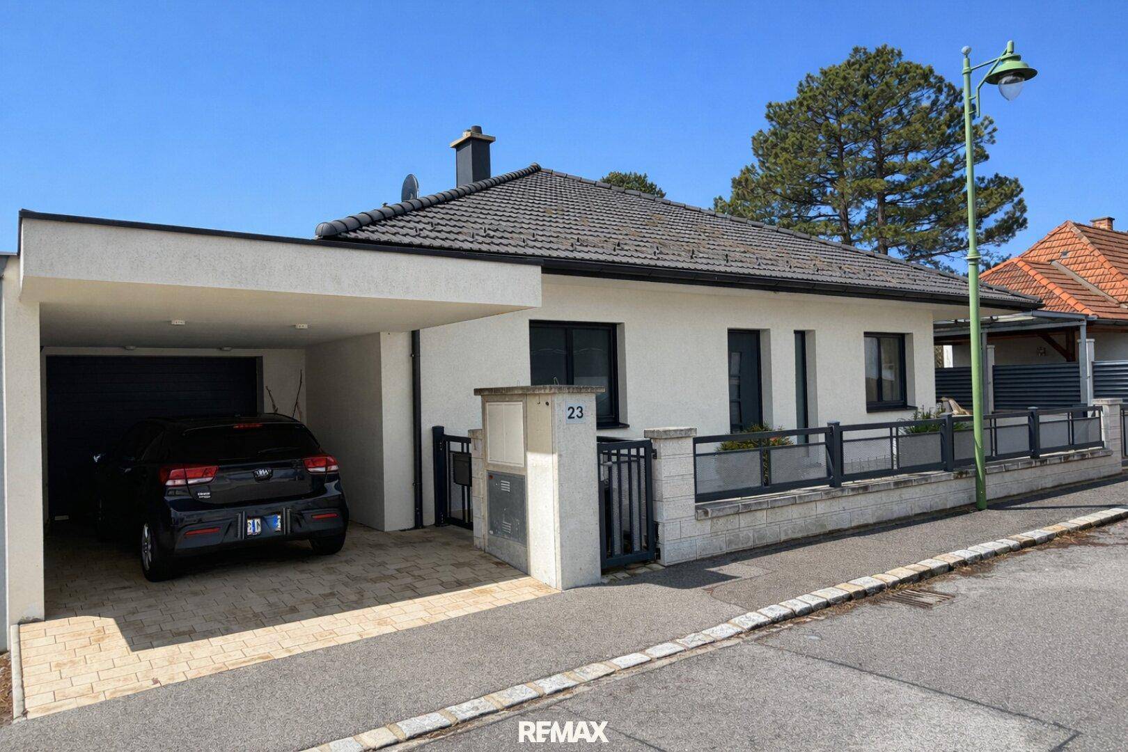 Vorderansicht des Hauses mit Carport, Einfahrt und gepflegtem Vorgartenbereich.