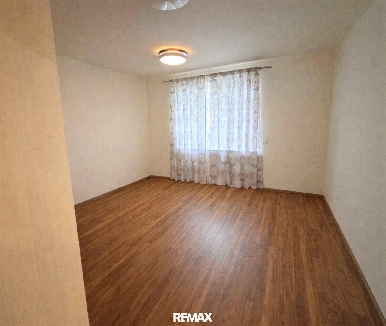 Freundliches Zimmer mit Holzboden und Fenster, bietet vielseitige Nutzungsmöglichkeiten.