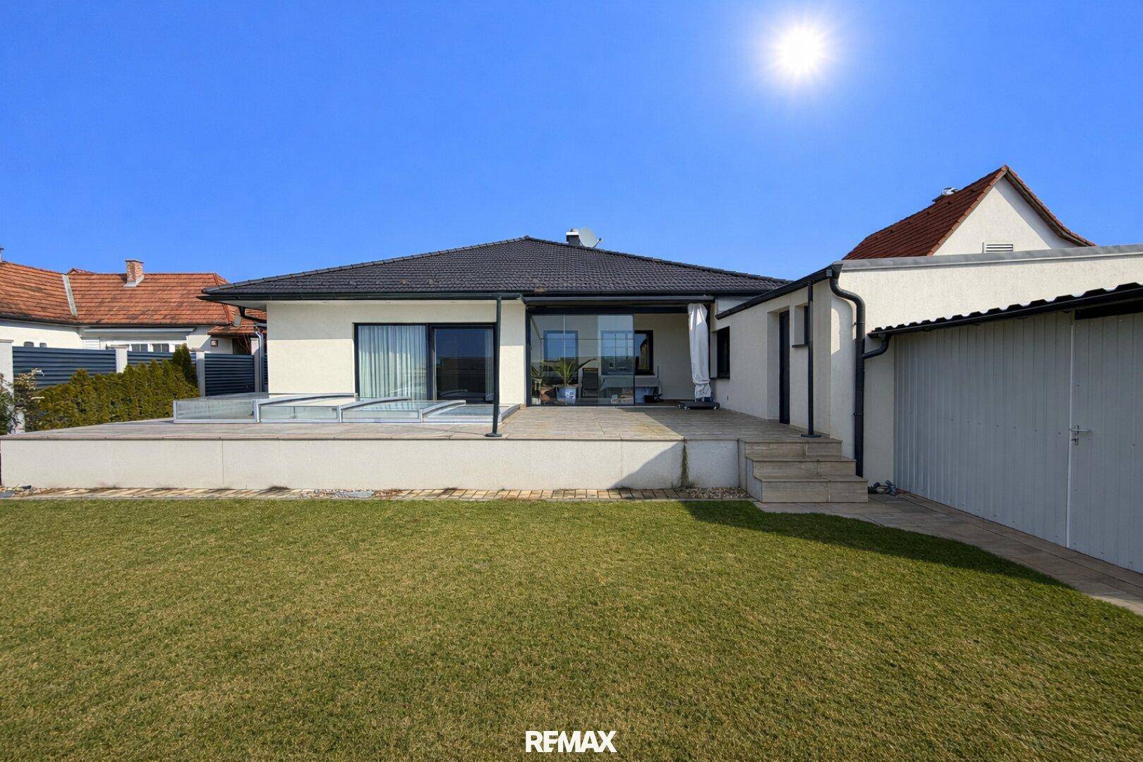 Rückansicht des modernen Einfamilienhauses mit großer Terrasse und gepflegtem Gartenbereich.