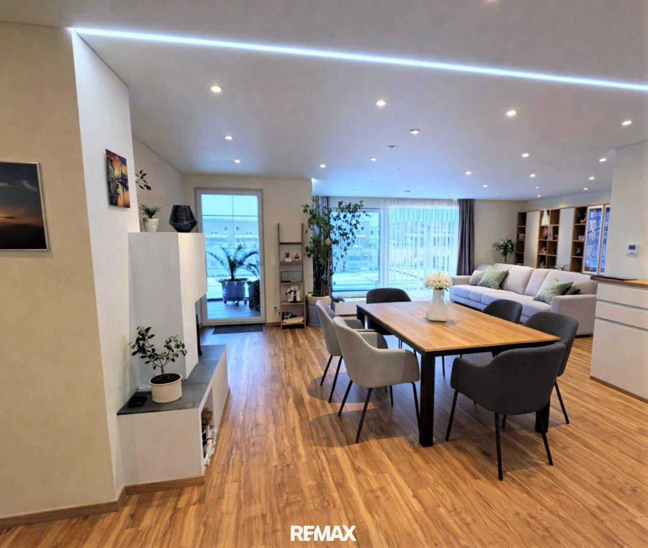 Heller, offener Wohn-Essbereich mit modernem Kamin, Holzboden und Zugang zur Terrasse.