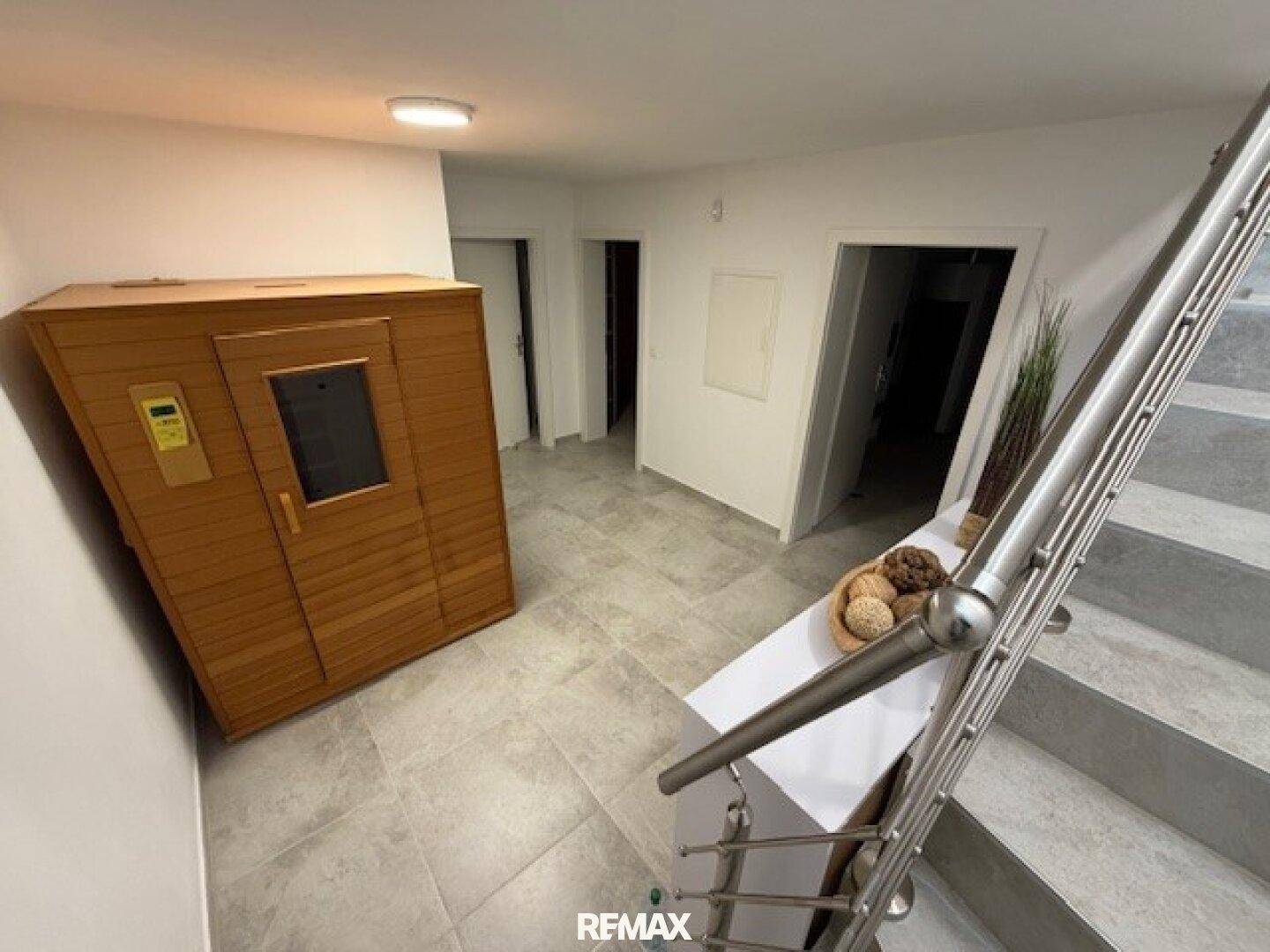Flur im Untergeschoss mit integrierter Sauna und Zugang zu weiteren Räumen über eine Treppe.